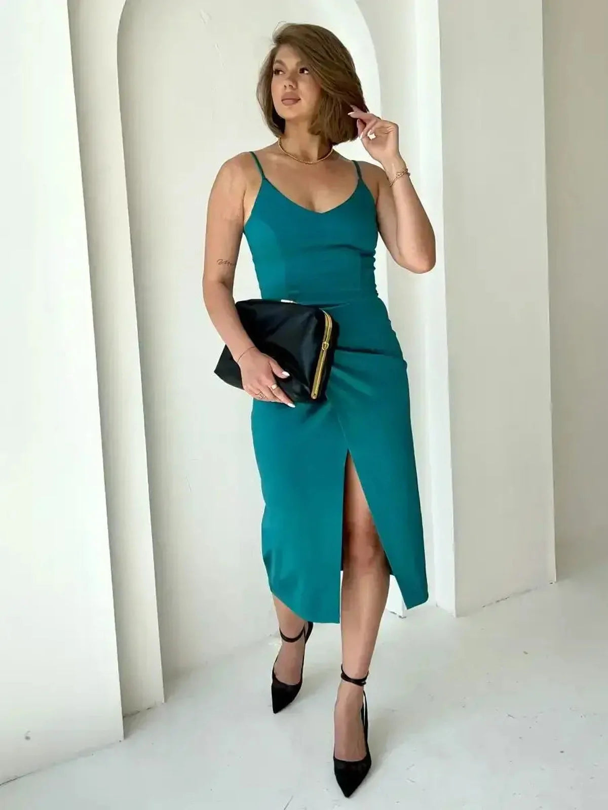 Model wearing a teal Lustre Midi Dress with a thigh-high slit, paired with a black clutch and heels.