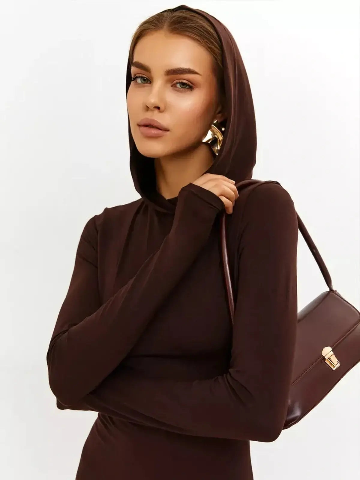 Model wearing a chocolate-toned Sculpt Maxi Dress with a hood, showcasing a sleek silhouette and modern elegance.