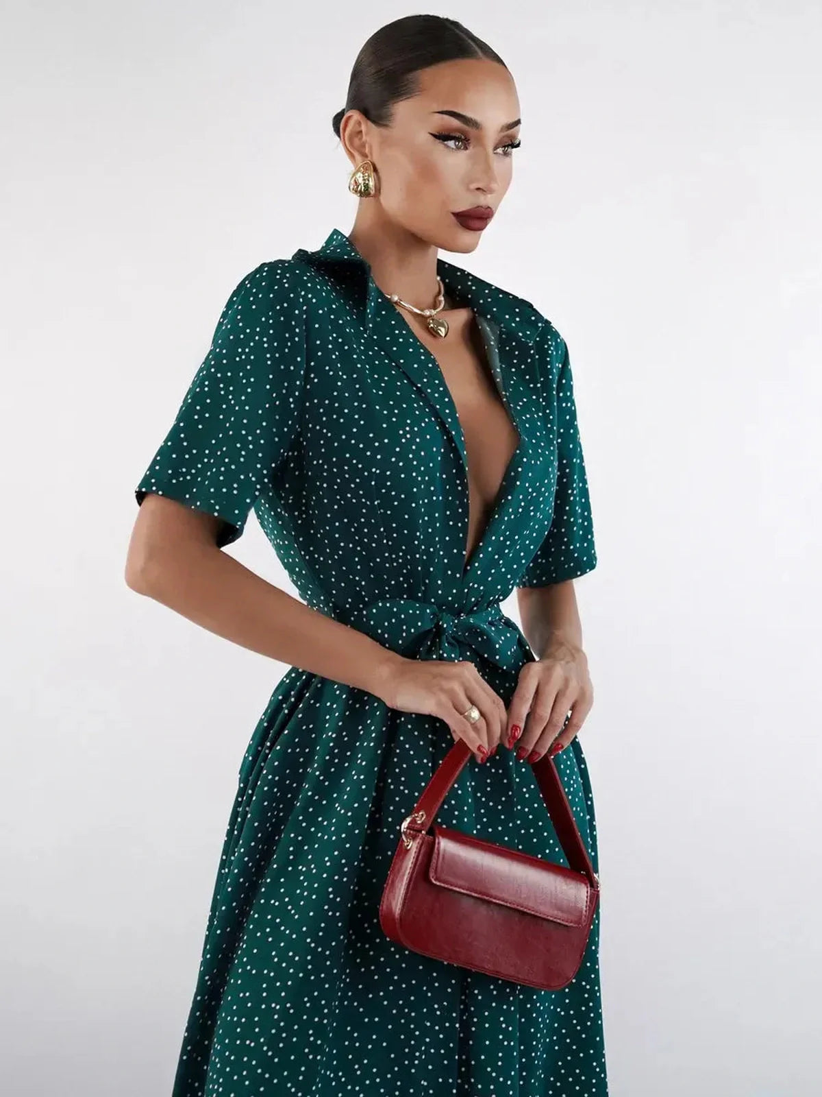 Model showcasing the Emerald Dot Midi Dress, featuring a green polka dot design and cinched waist, perfect for summer occasions.
