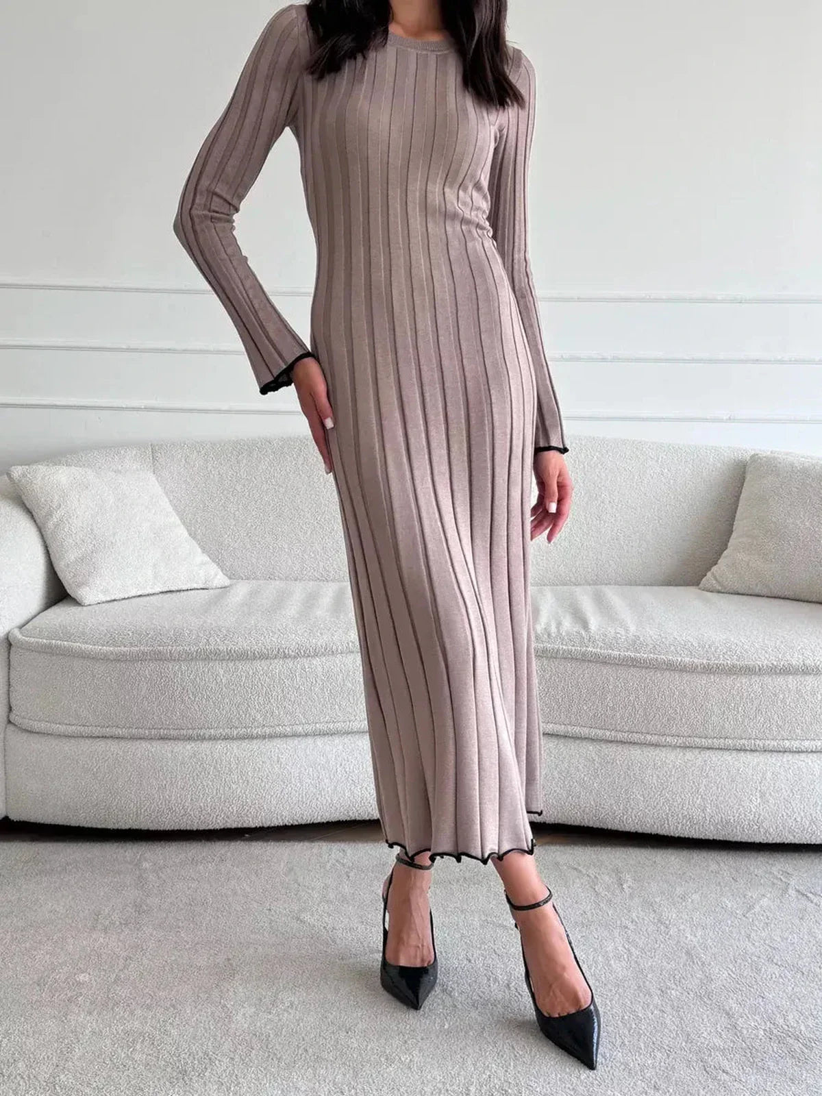 Woman wearing a ribbed knit Contour Maxi Dress with a full-length silhouette and elegant ruffle hem, styled with black heels.