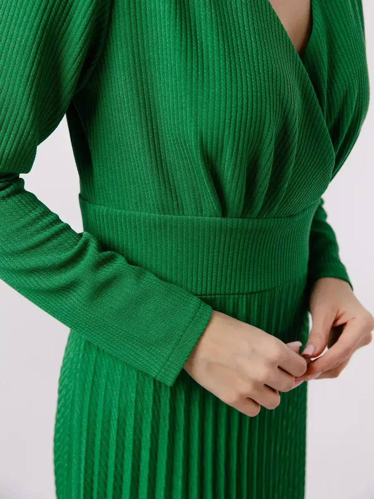 Close-up of a woman's hands adjusting the waist of the Emerald Grace Midi Dress in vibrant green texture.
