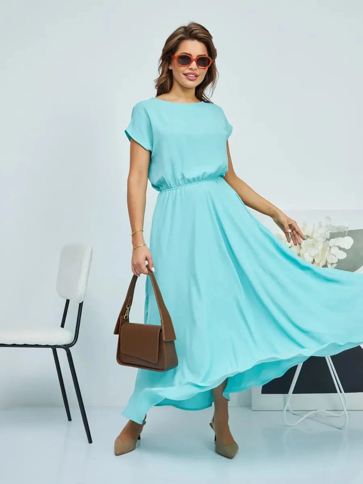 Model wearing a flowy turquoise maxi dress with a cinched waist, perfect for summer events and casual outings.