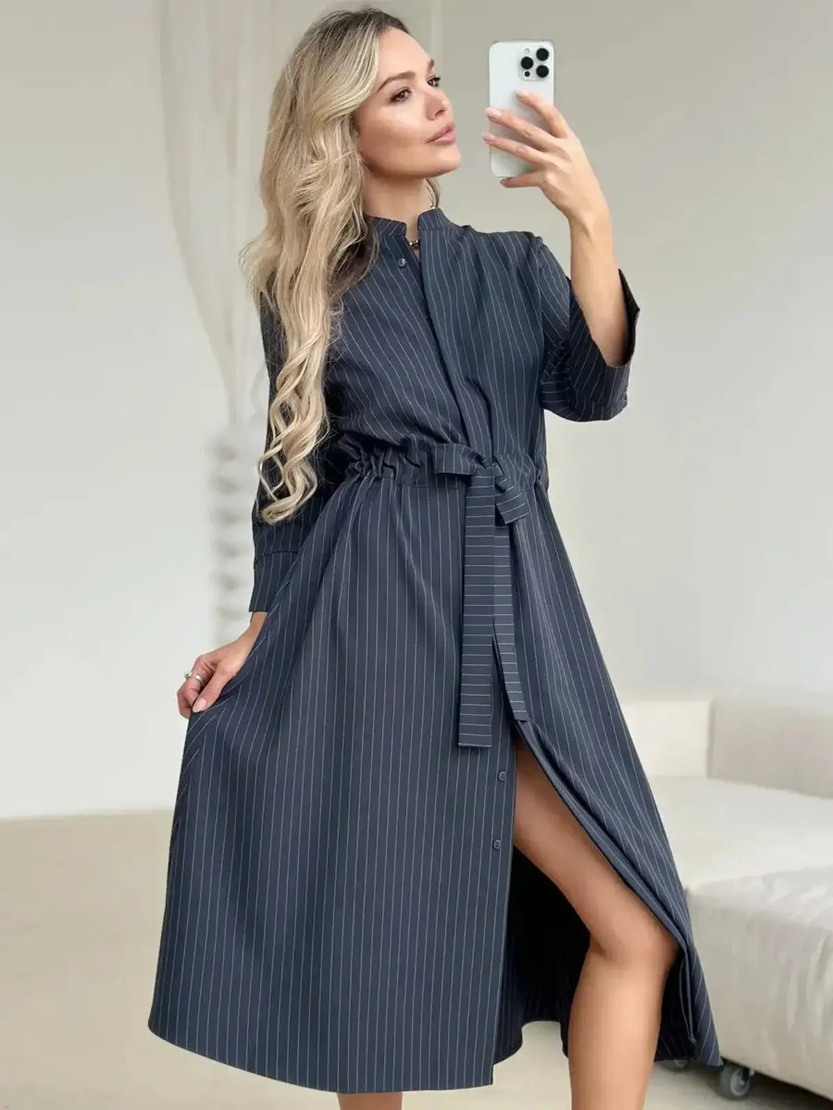 Stylish woman modeling a slate stripe midi dress with a waist tie, featuring a relaxed fit and elegant pinstripes.