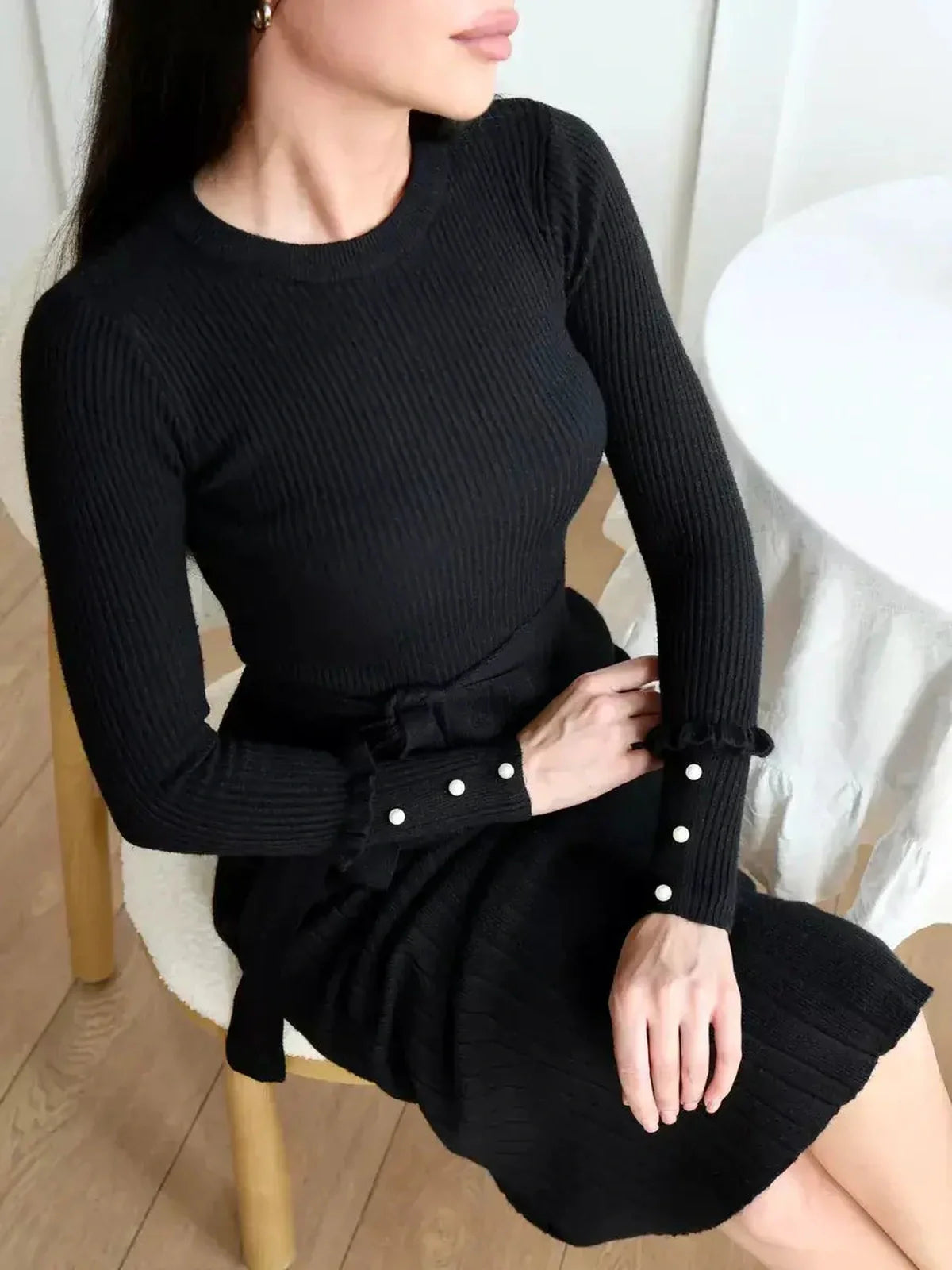 Woman wearing the Midnight Grace Midi Dress in black, featuring ribbed knit and pearl details on the cuffs.