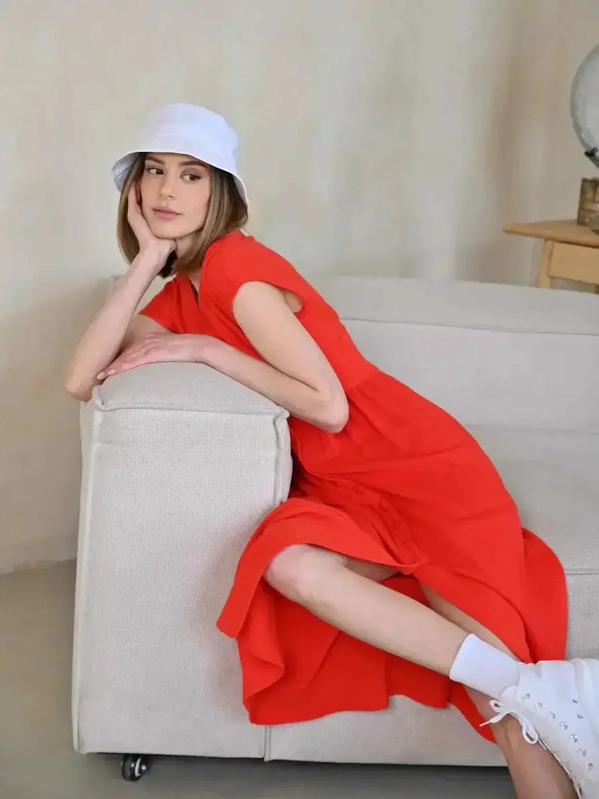 Model wearing Flare Muse Midi Dress in radiant red, styled with a summer hat, reflecting casual elegance.