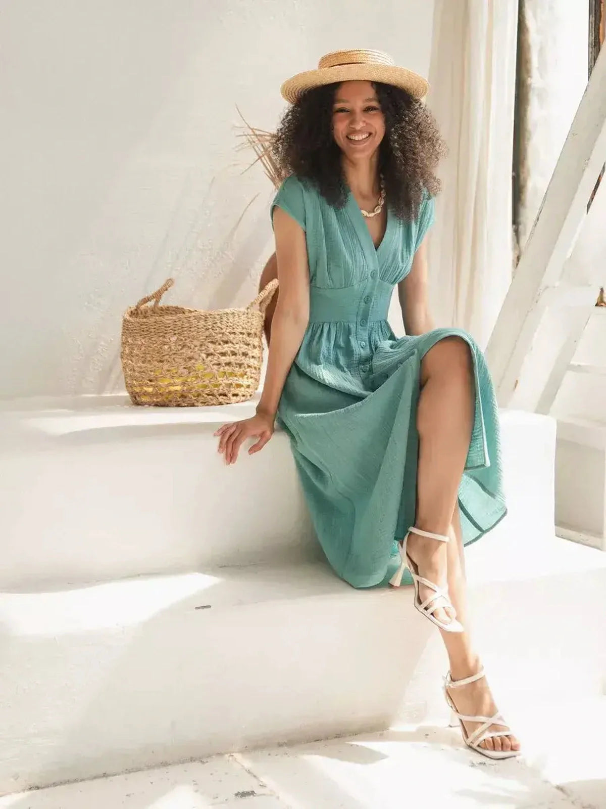 Woman wearing a Veranda Midi Dress in sea-green, showcasing a V-neckline and corset waistband, perfect for summer outings.