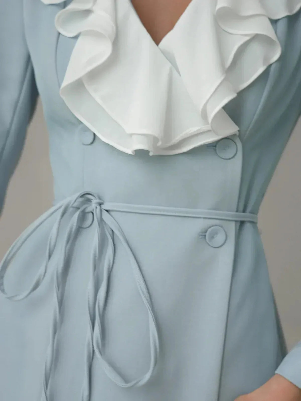 Close-up of the Celeste Ruffle Mini, featuring a sky blue dress with a white ruffle neckline and elegant tie detail.
