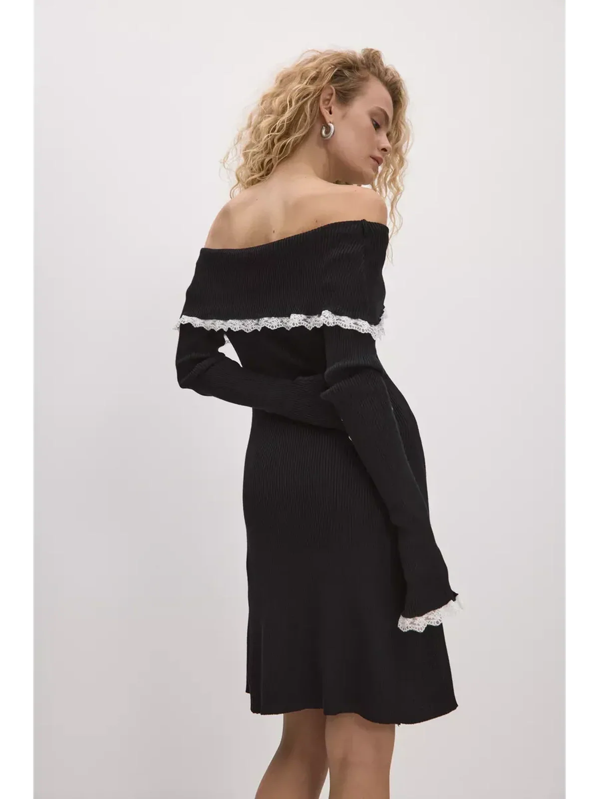 Model showcasing a black lace off-shoulder mini dress with a vintage edge and long sleeves.