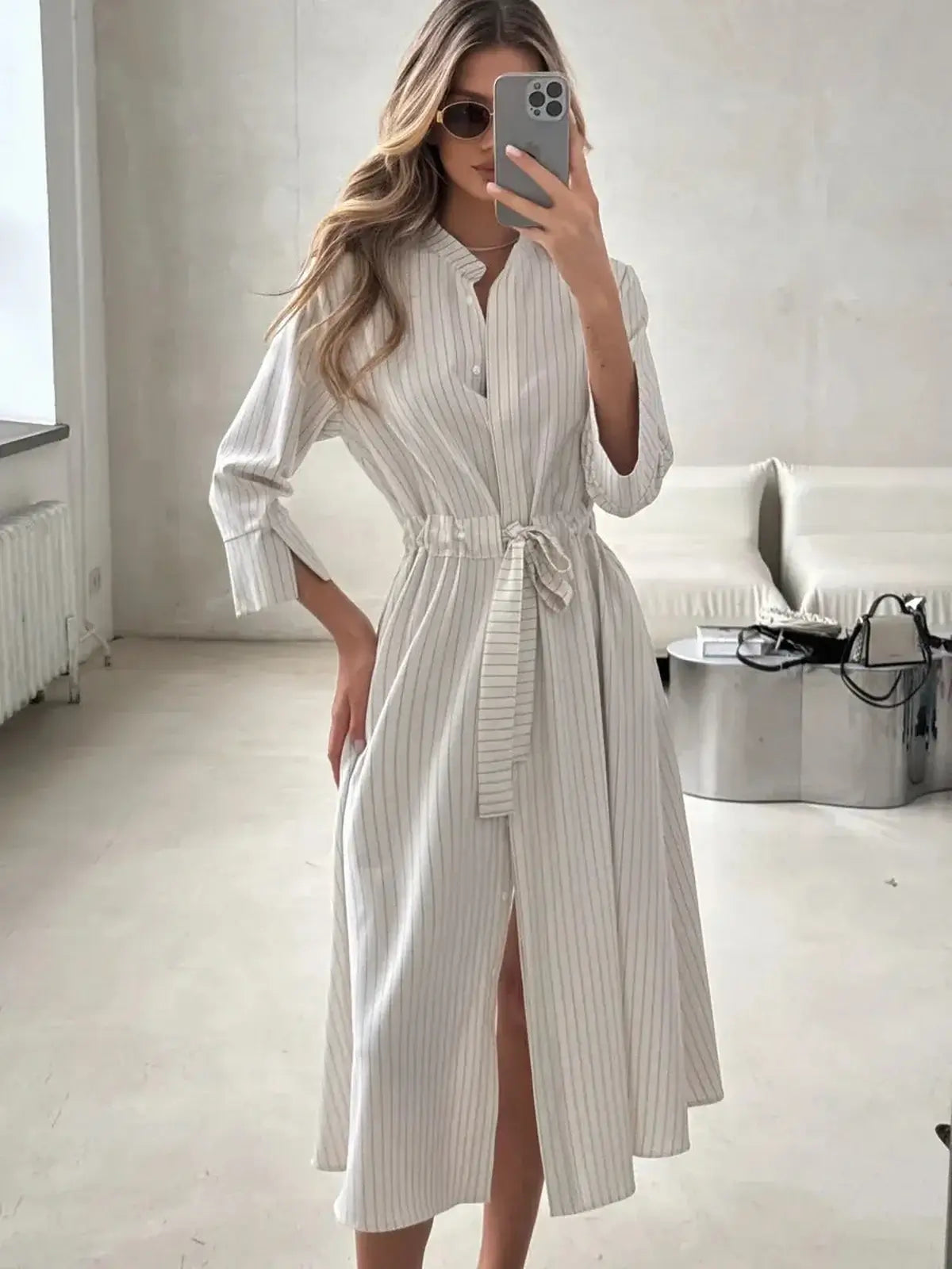 Elegant pinstripe midi dress with waist tie and front slit, perfect for business casual or summer outings.