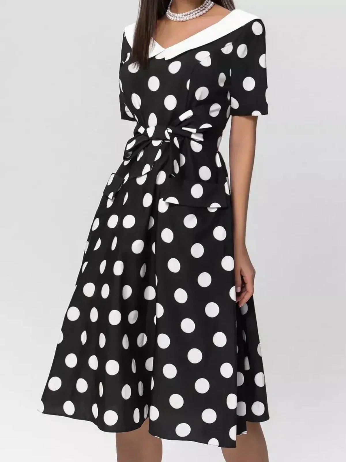 Elegant black and white polka dot midi dress with V-neck and tie waist, perfect for summer and formal events.