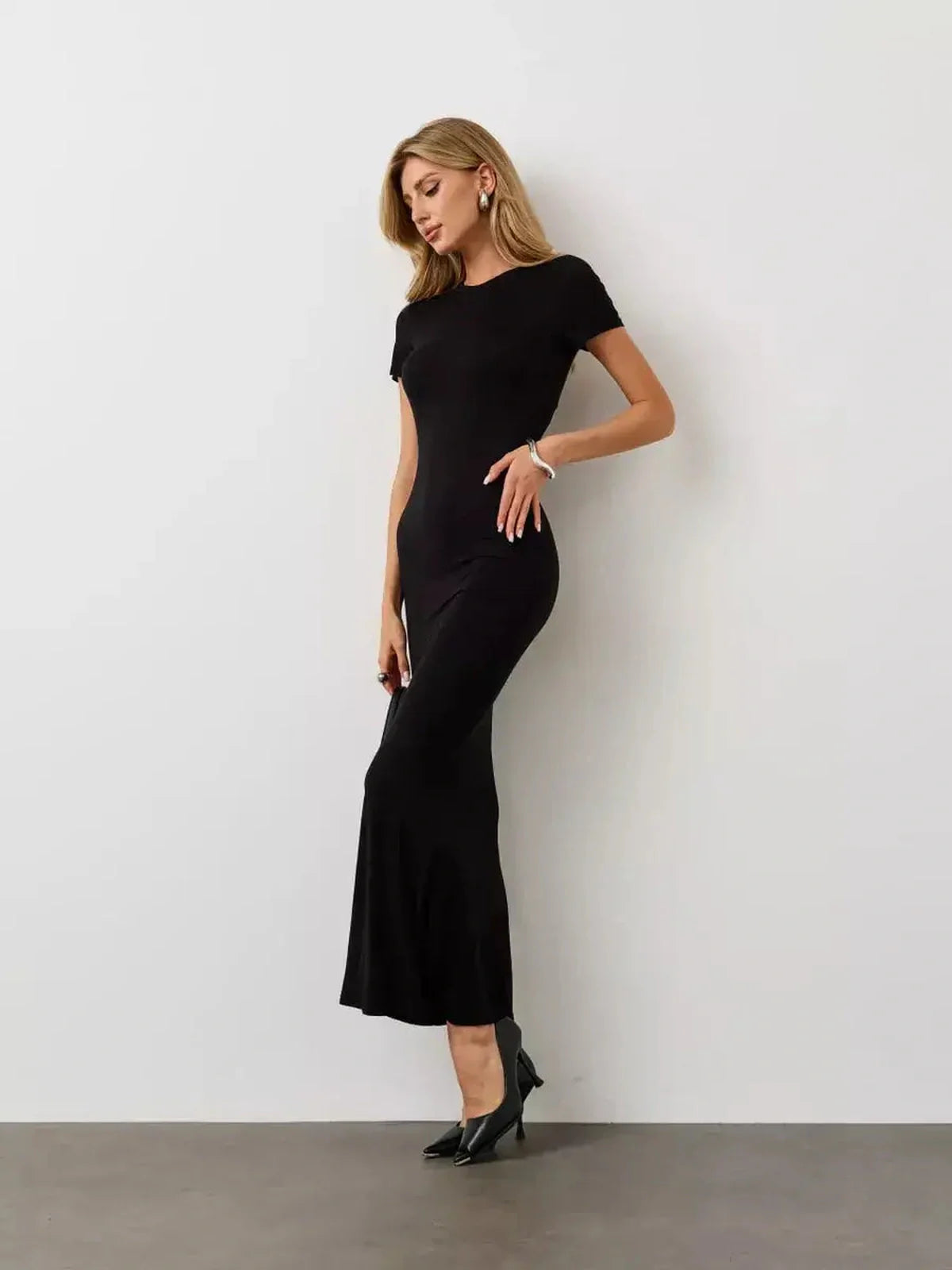 Model wearing a sleek Noir Curve Maxi Dress, showcasing a sculpted silhouette in iconic black, perfect for formal occasions.