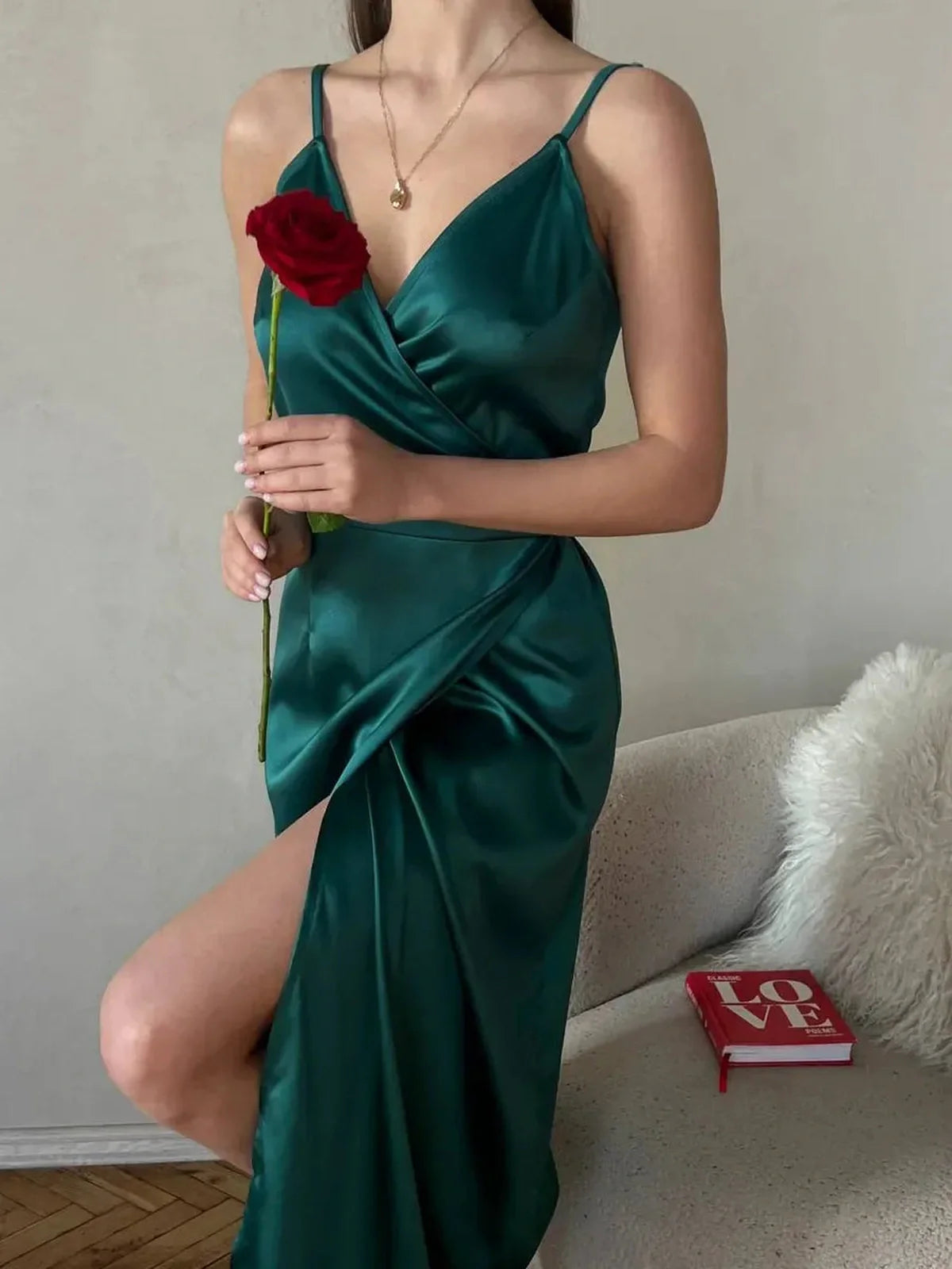 Model wearing an emerald satin wrap midi dress with a leg slit, holding a red rose, stylish and elegant for special occasions.