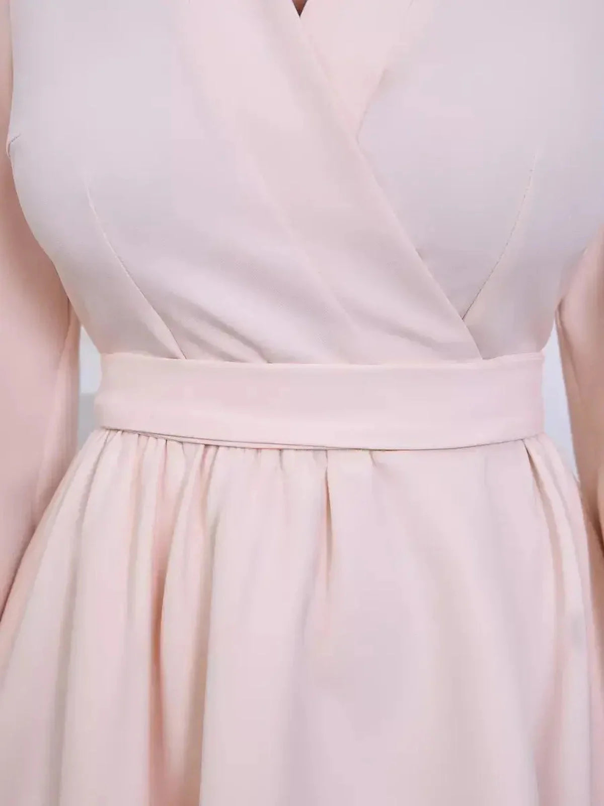 Close-up of a champagne-toned mini dress with a soft V-neck wrap, long puff sleeves, and a flattering fit-and-flare silhouette.