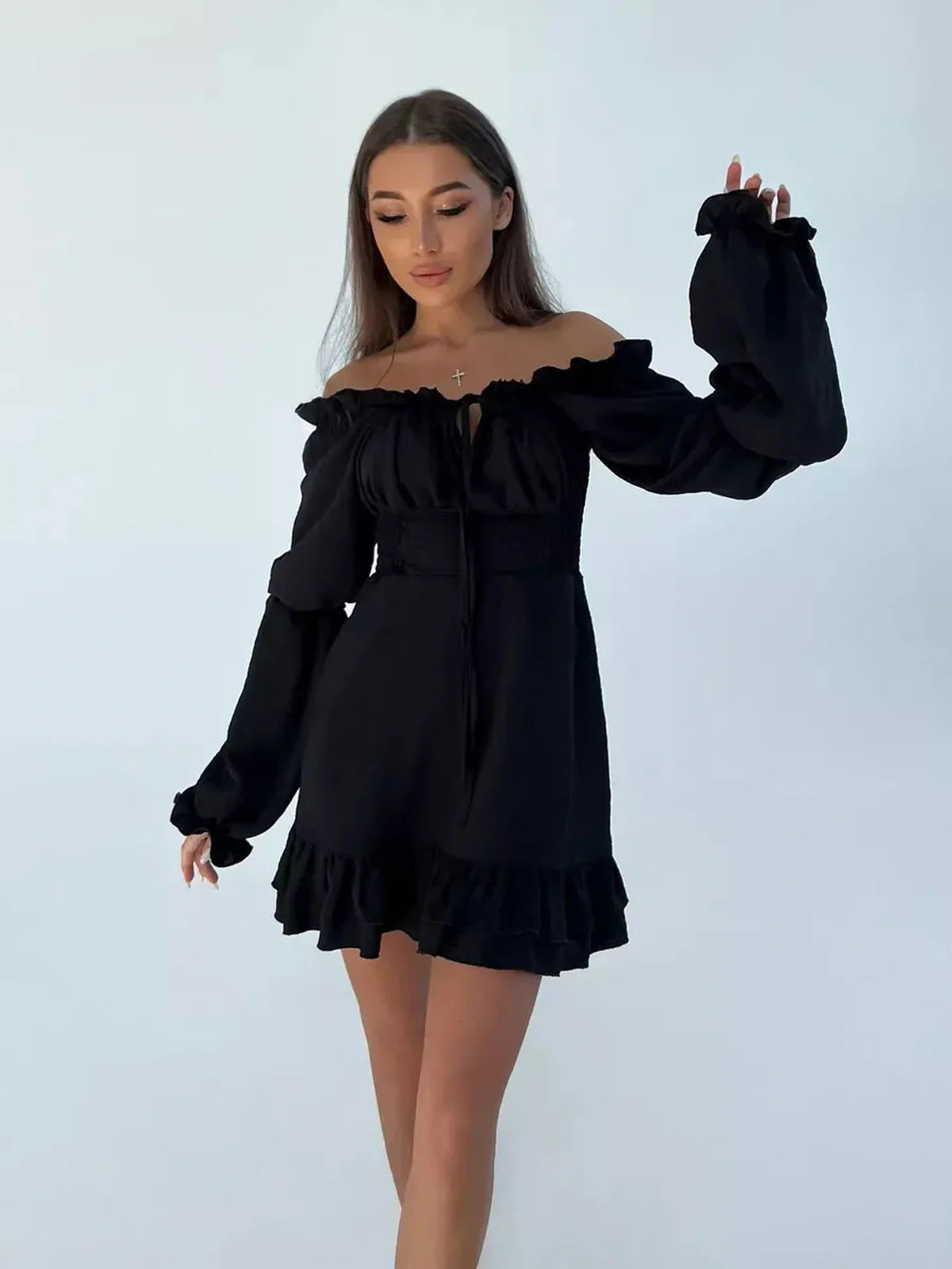Model wearing a black off-the-shoulder mini dress with ruffle sleeves and hem, perfect for summer parties.