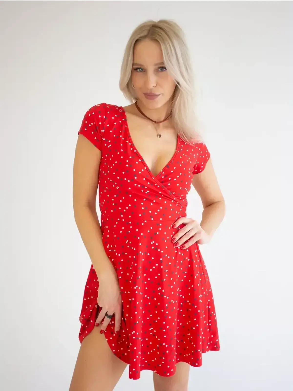Model wearing a flirty red mini dress with polka dots and a V-neckline, perfect for summer and special occasions.