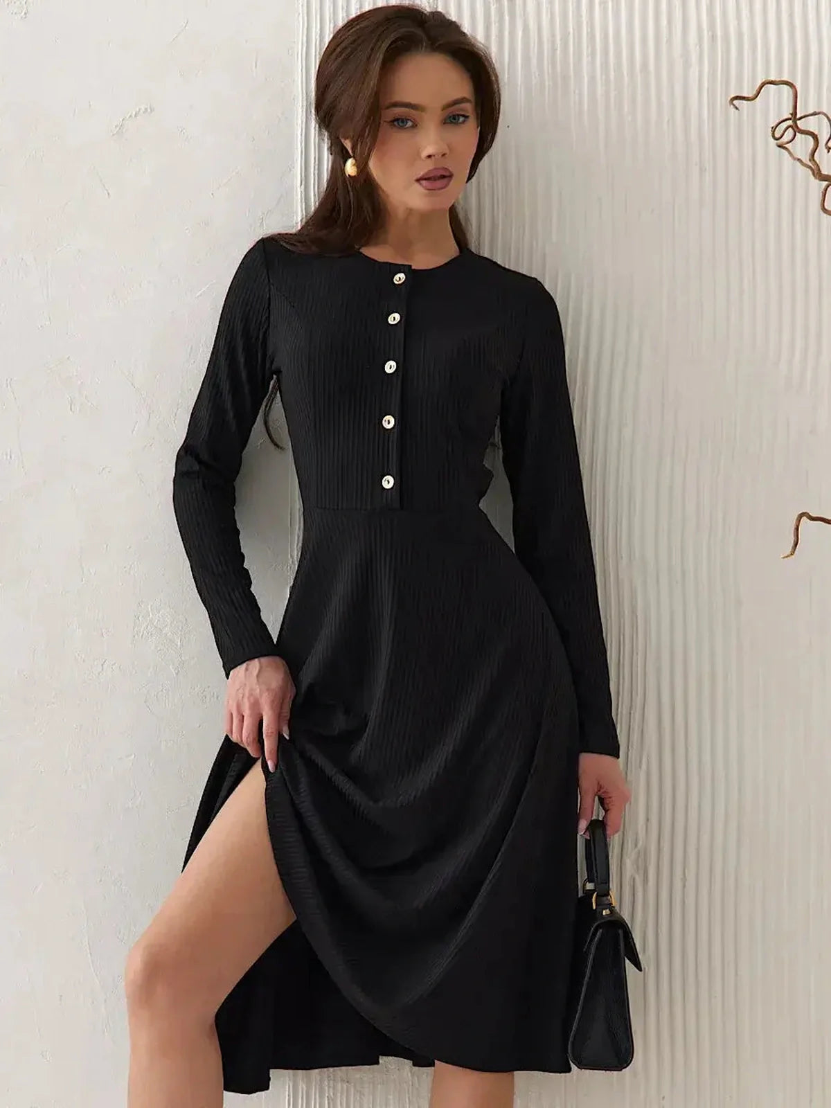 Elegant black midi dress with ribbed texture, long sleeves, and decorative buttons, perfect for formal and casual occasions.