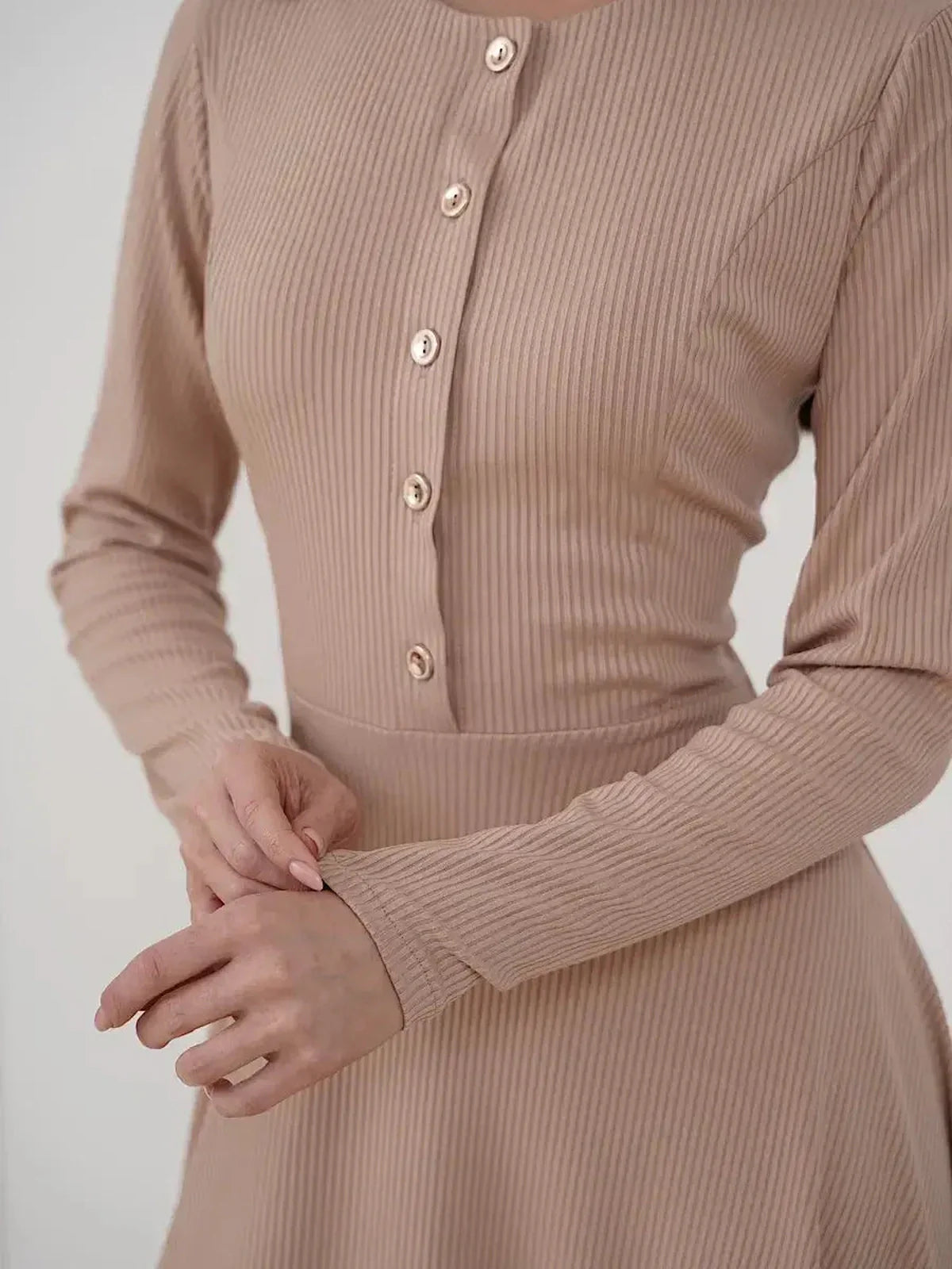Close-up of a woman wearing the Sculpted Ease Midi Dress in beige, featuring ribbed knit texture and gold-tone buttons.