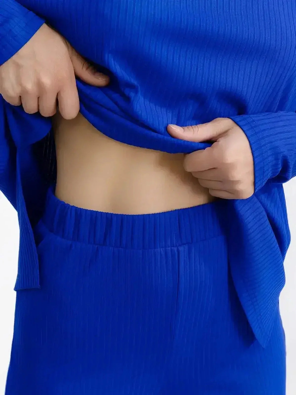 Close-up of a woman adjusting the oversized Electric Lounge Set in vibrant electric blue, showcasing its ribbed knit texture.