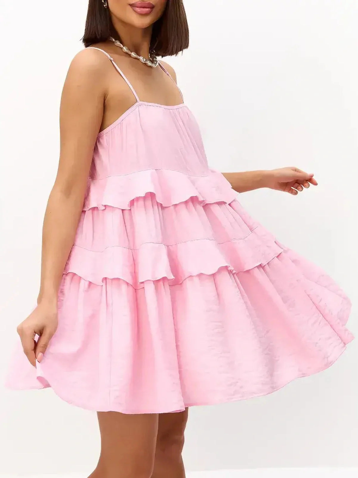 Playful pink mini dress with tiered ruffles and spaghetti straps, perfect for summer occasions and weddings.