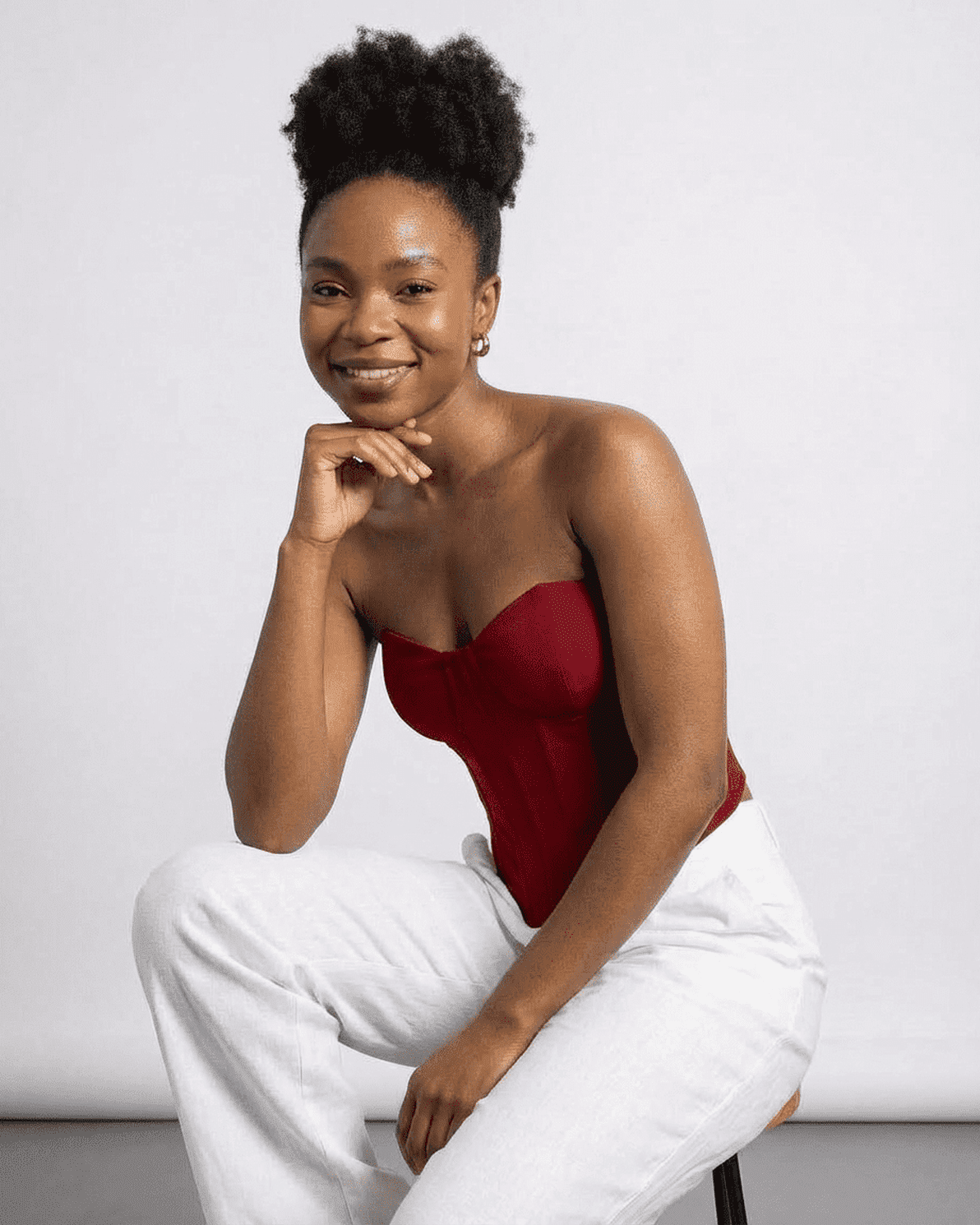 Smiling model wearing the Slimona Crimson Corset Top, a faux denim cup bustier, styled with light pants.