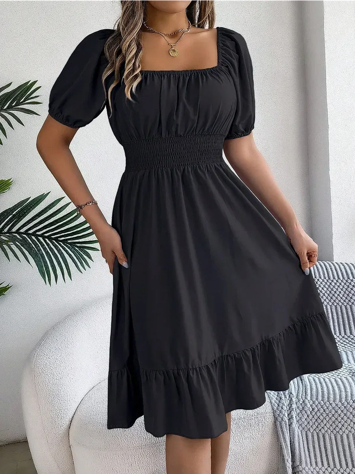 Black mini dress with structured square neckline and puff sleeves, ideal for summer occasions and weddings.