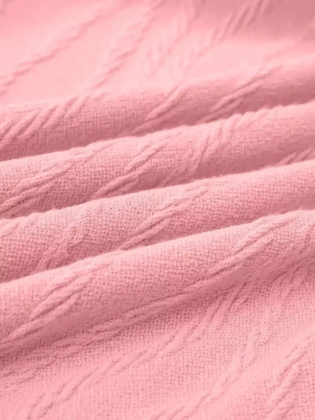 Close-up of soft pink textured fabric showcasing intricate knit details, ideal for stylish summer or casual dresses.