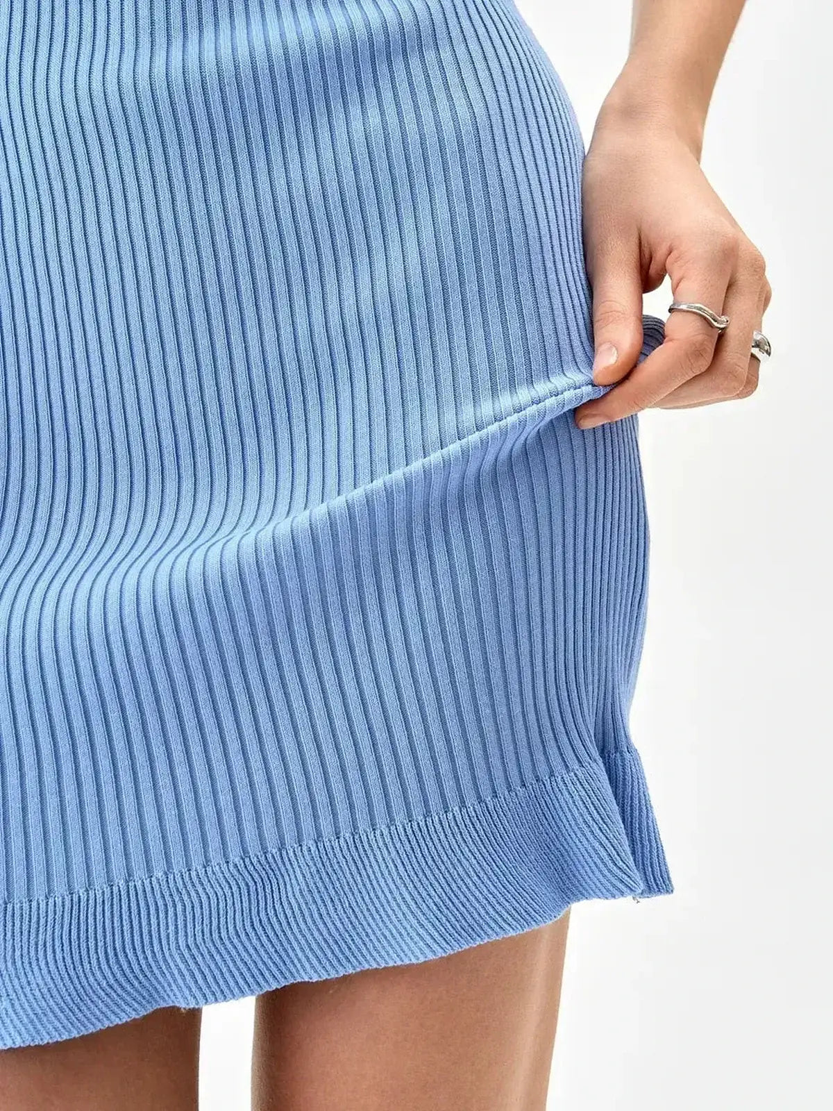 Close-up of a blue ribbed knit dress featuring a flared hem and softly gathered detail.