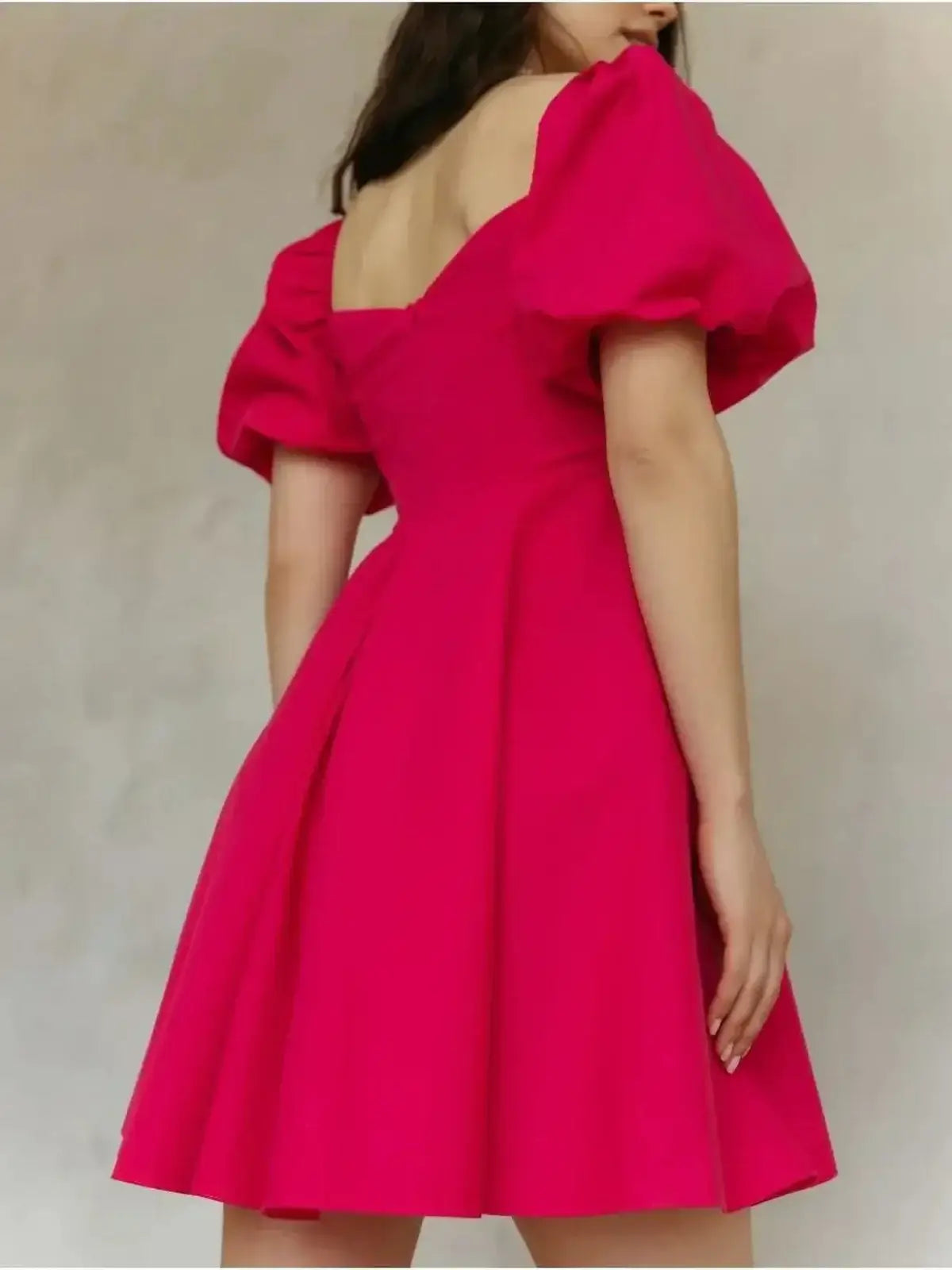 Model wearing a bright pink Rose Fizz Mini Dress with puff sleeves and flared skirt, perfect for summer and wedding guest occasions.