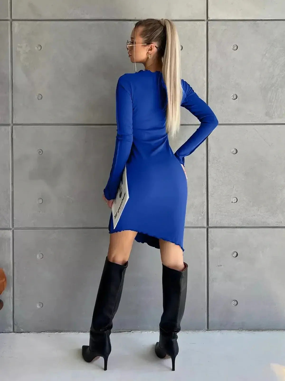 Model showcases the Sculpt Mini vibrant blue long sleeve dress, featuring a body-hugging fit and stylish raw-edge hem.