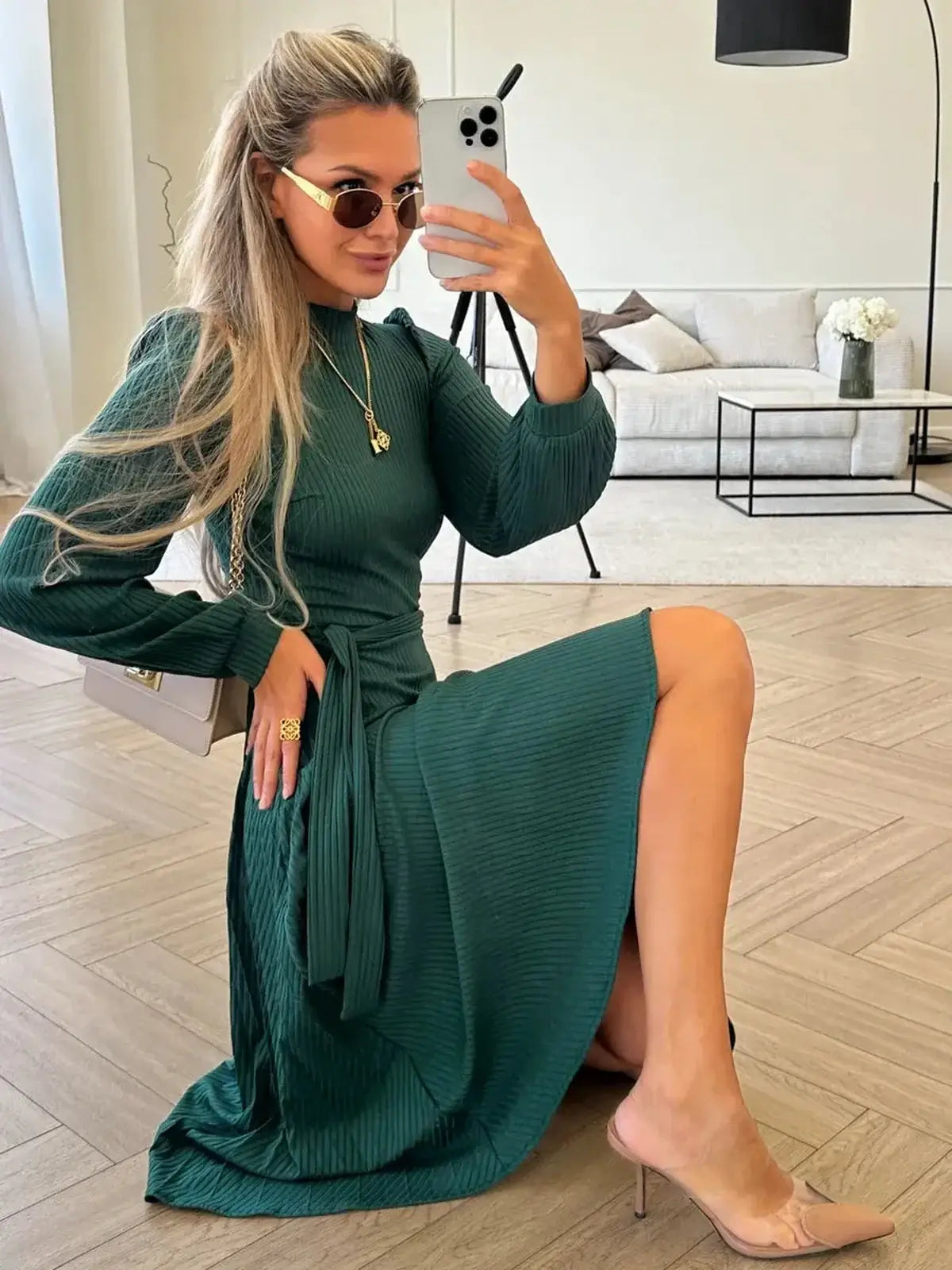 Model showcasing the Emerald Poise Midi Dress in emerald green, featuring ribbed texture and pleated skirt.