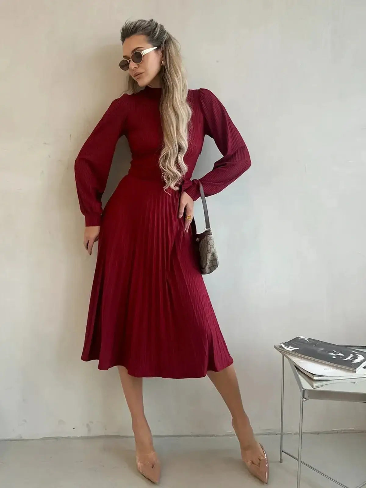 Model wearing a crimson midi dress with pleats, showcasing timeless elegance for formal occasions.