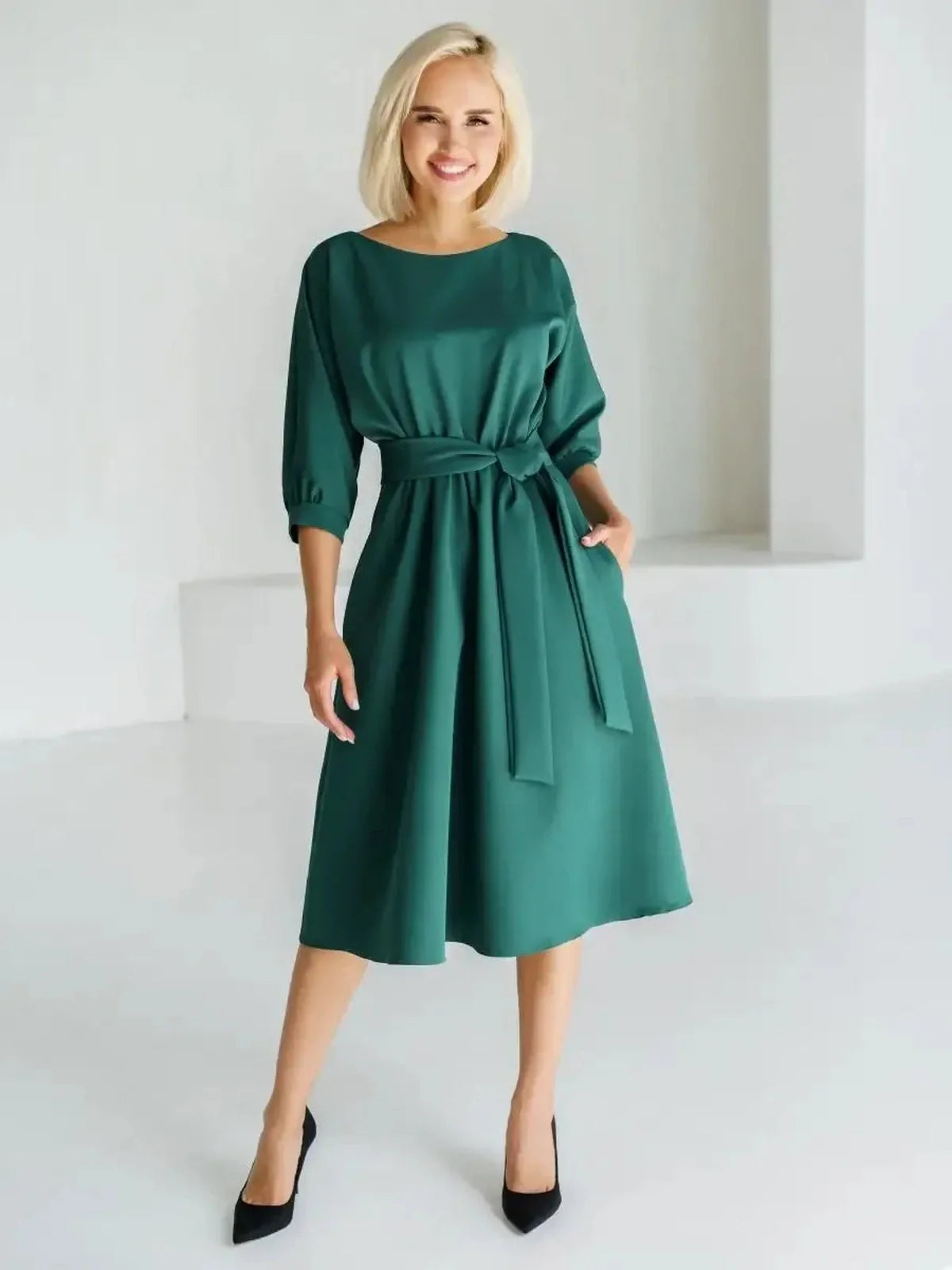 Sophisticated woman wearing an emerald green midi dress with a belted waist and boat neckline, perfect for various occasions.