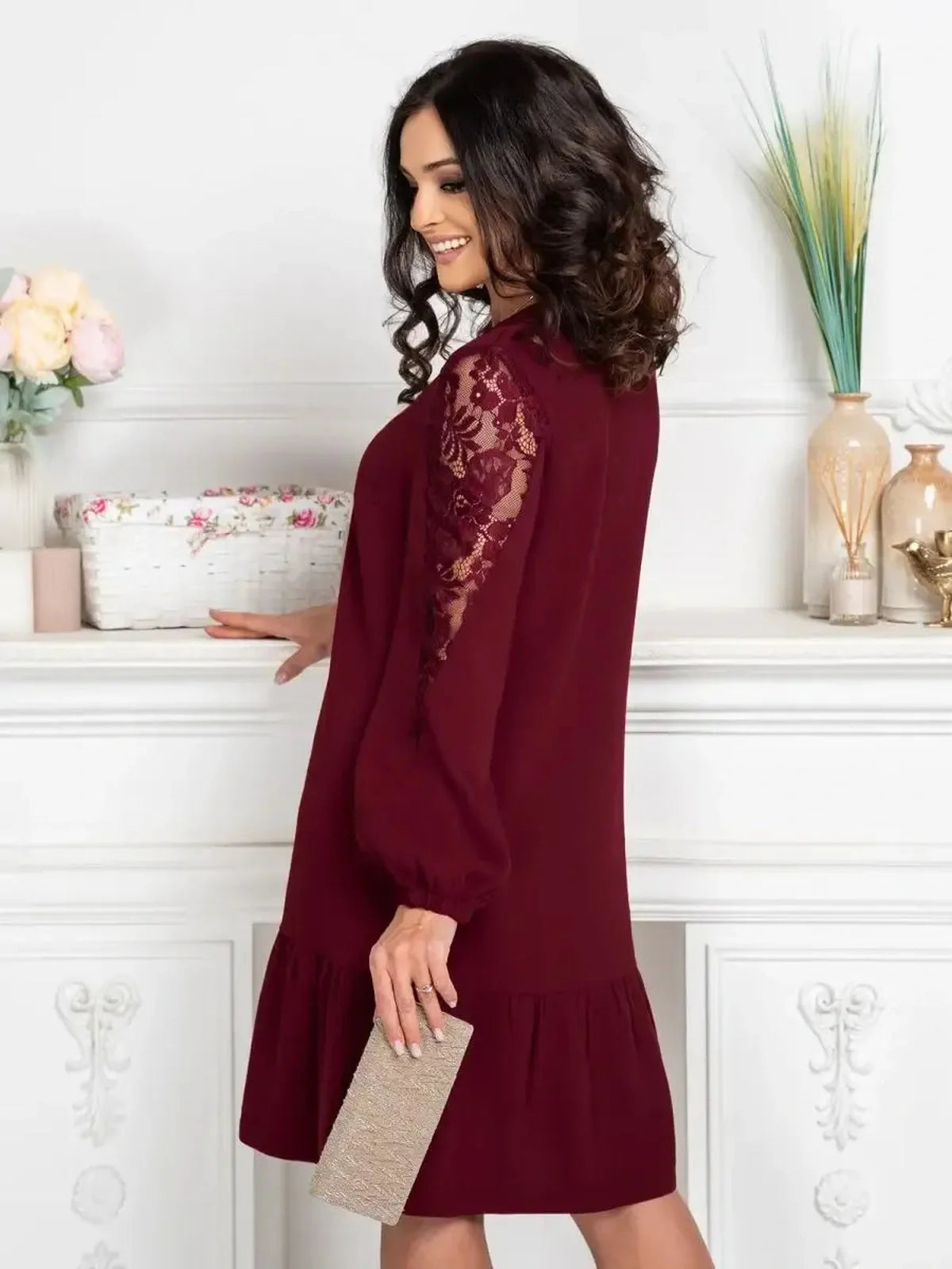 Woman wearing a chic Lace Ruby mini dress with sheer lace sleeves and ruffle hem, perfect for formal or casual occasions.