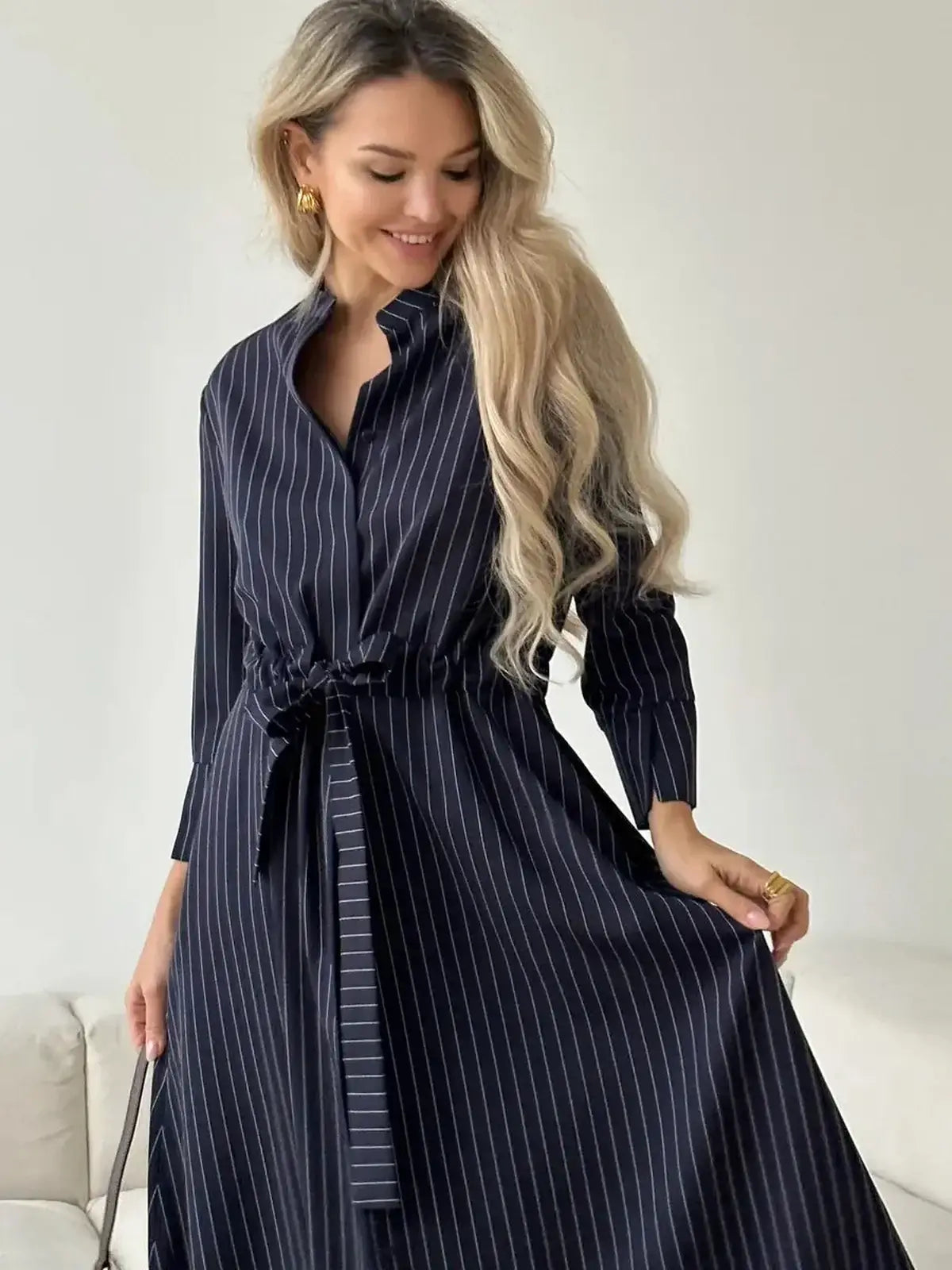 Elegant woman in a pinstripe midi dress with a self-tie waist, perfect for casual and formal occasions.
