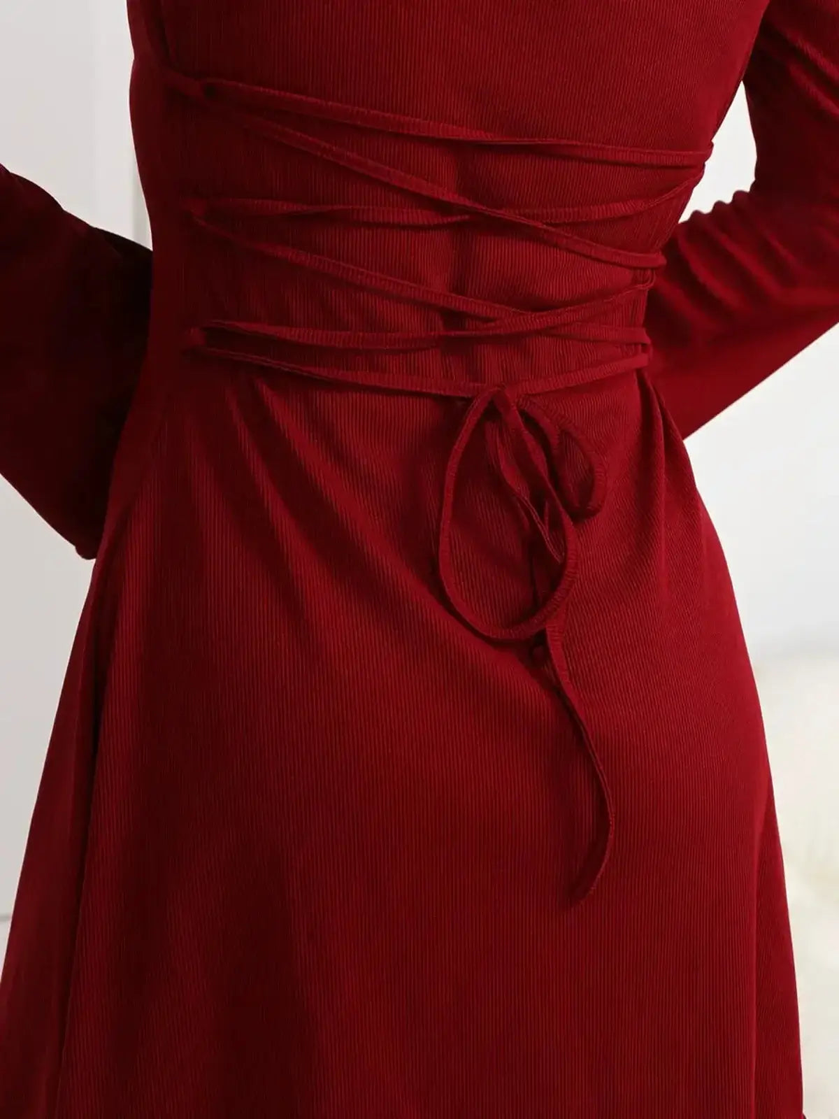 Close-up of the lace-up back detail of a Ruby Laced red dress, showcasing its elegant corset design.