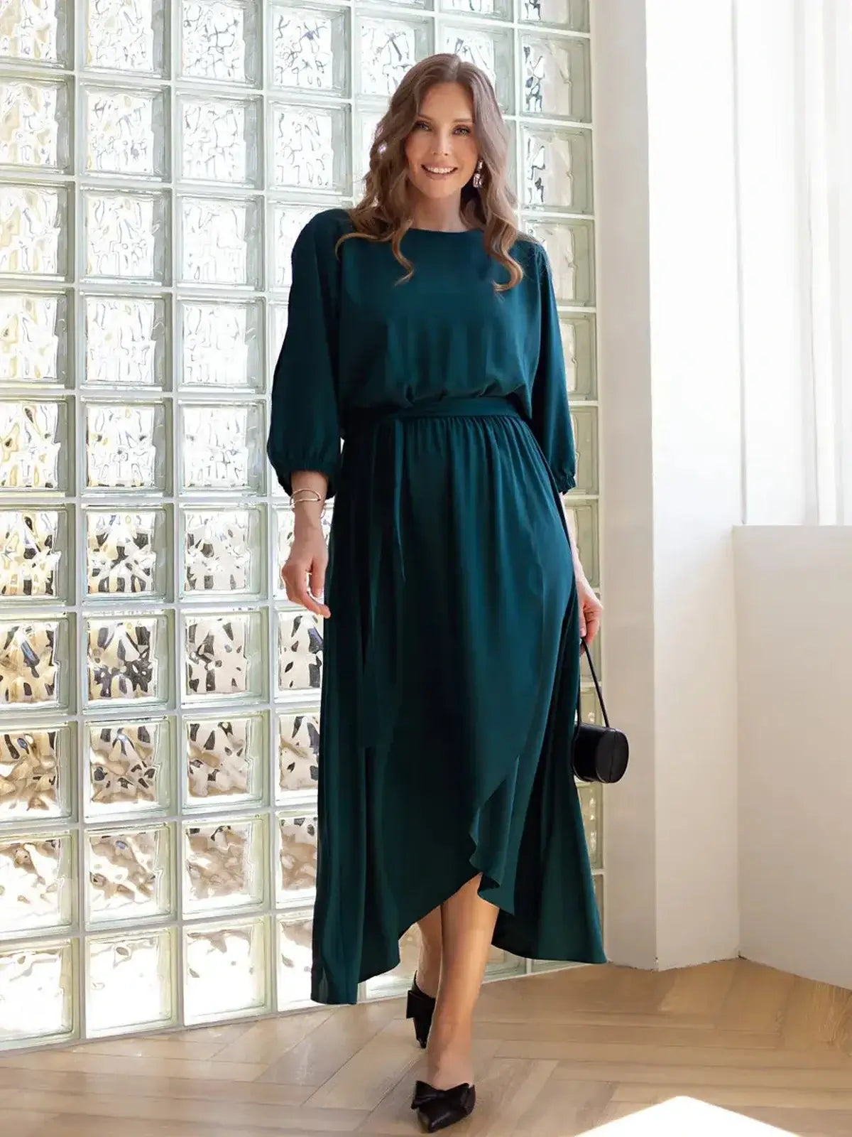 Model wearing a cascade midi dress with draped elegance and shoulder cutouts, perfect for weddings and formal occasions.