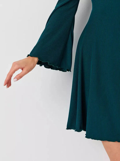 Elegant detail of the Emerald Whisper mini dress featuring bell sleeves and a flared hem in rich emerald green.