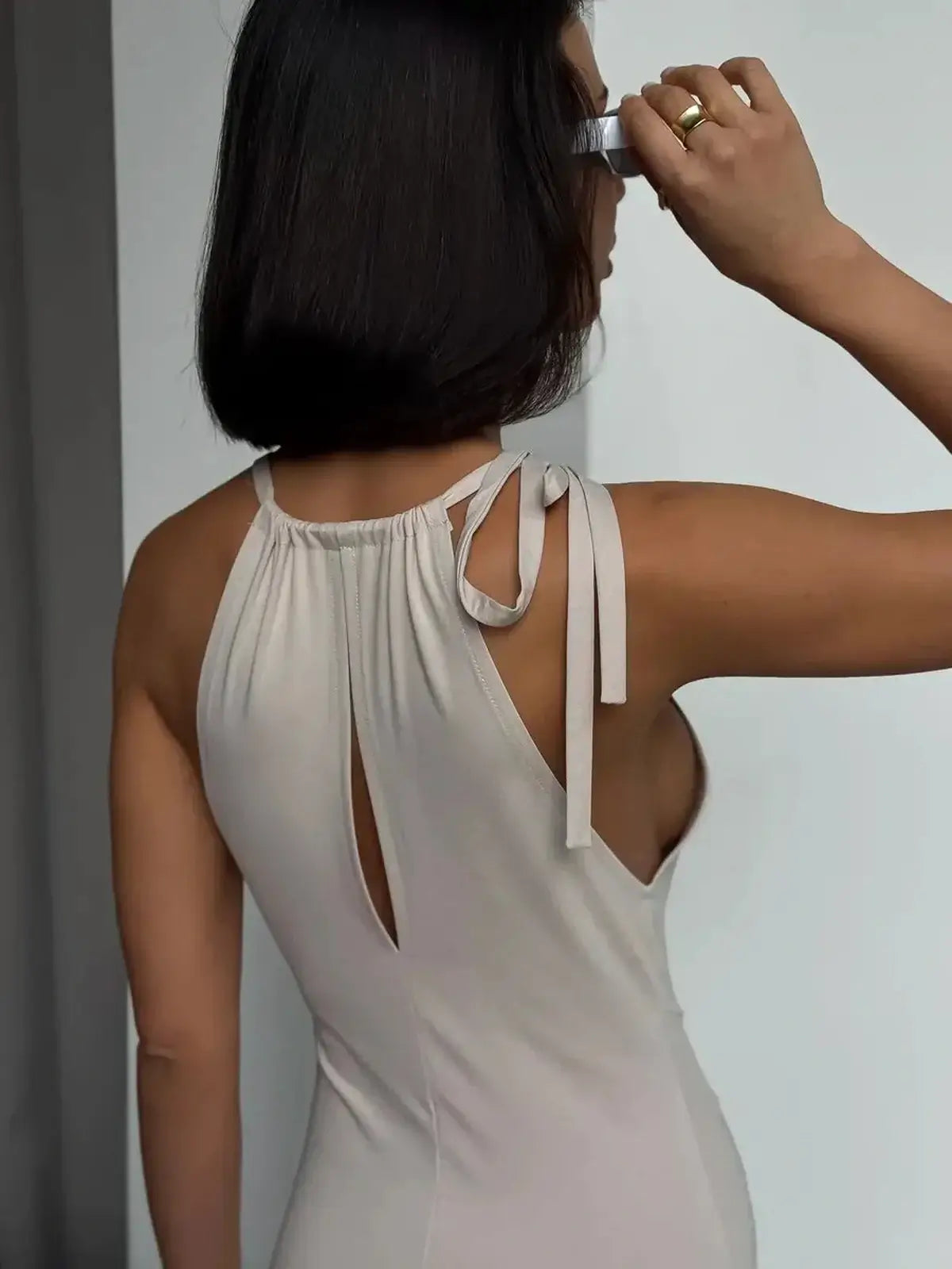 Back view of a woman showcasing the Serene Curve Maxi Dress with halter neck and tie-back detail.