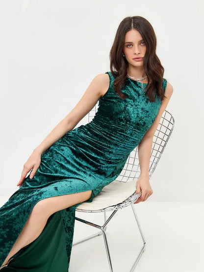Model wearing the Velvet Aura Maxi Dress in rich green velvet, featuring a high slit and elegant ruching, perfect for formal occasions.