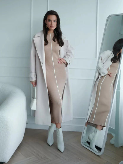 Model in a soft beige Sculpted Line Midi Dress paired with a light coat, showcasing elegant lines and a sophisticated look.