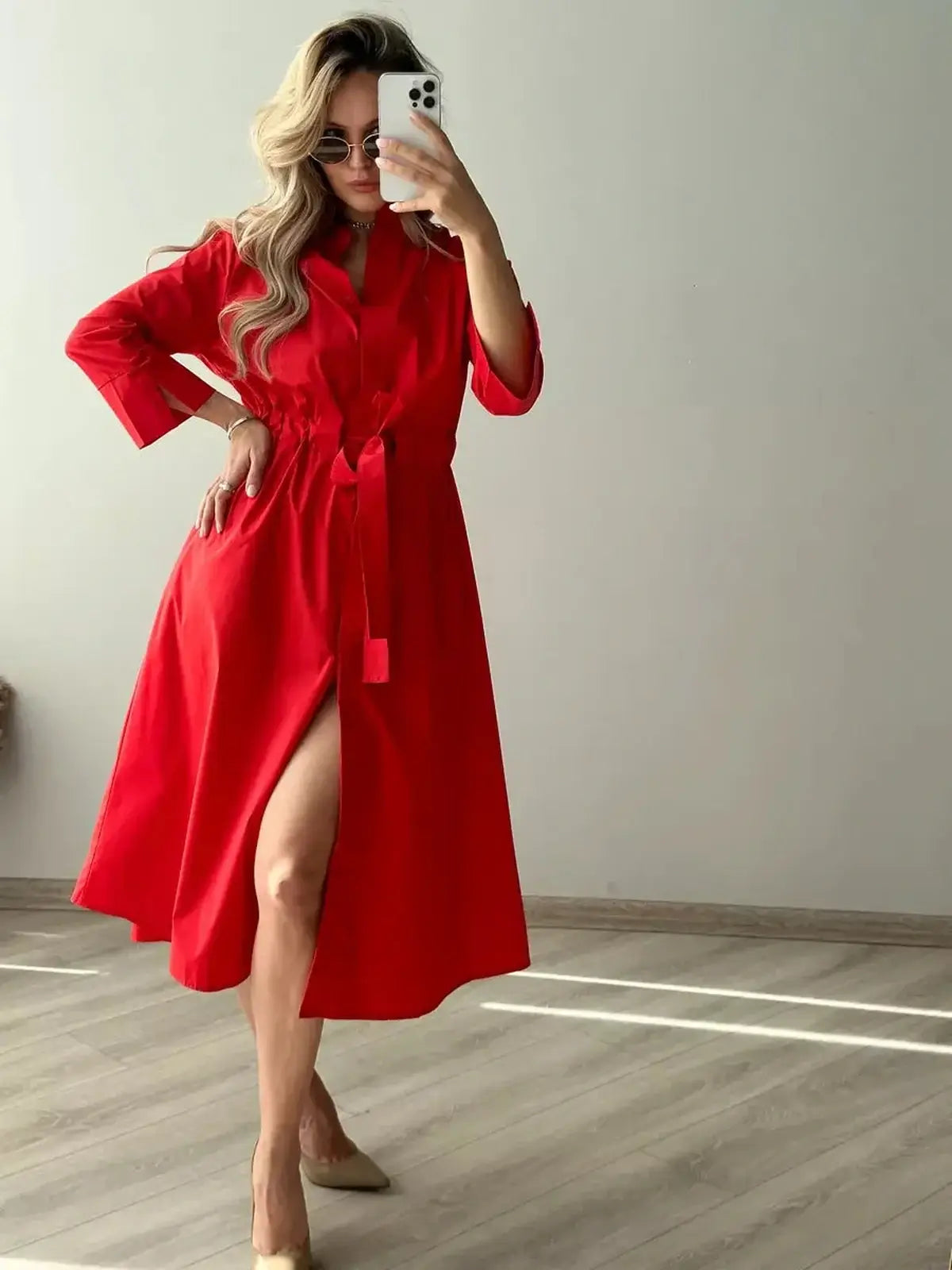 Model showcasing the Crimson Ease Midi Dress in vibrant red, featuring a belted waist and side slit for a flattering silhouette.