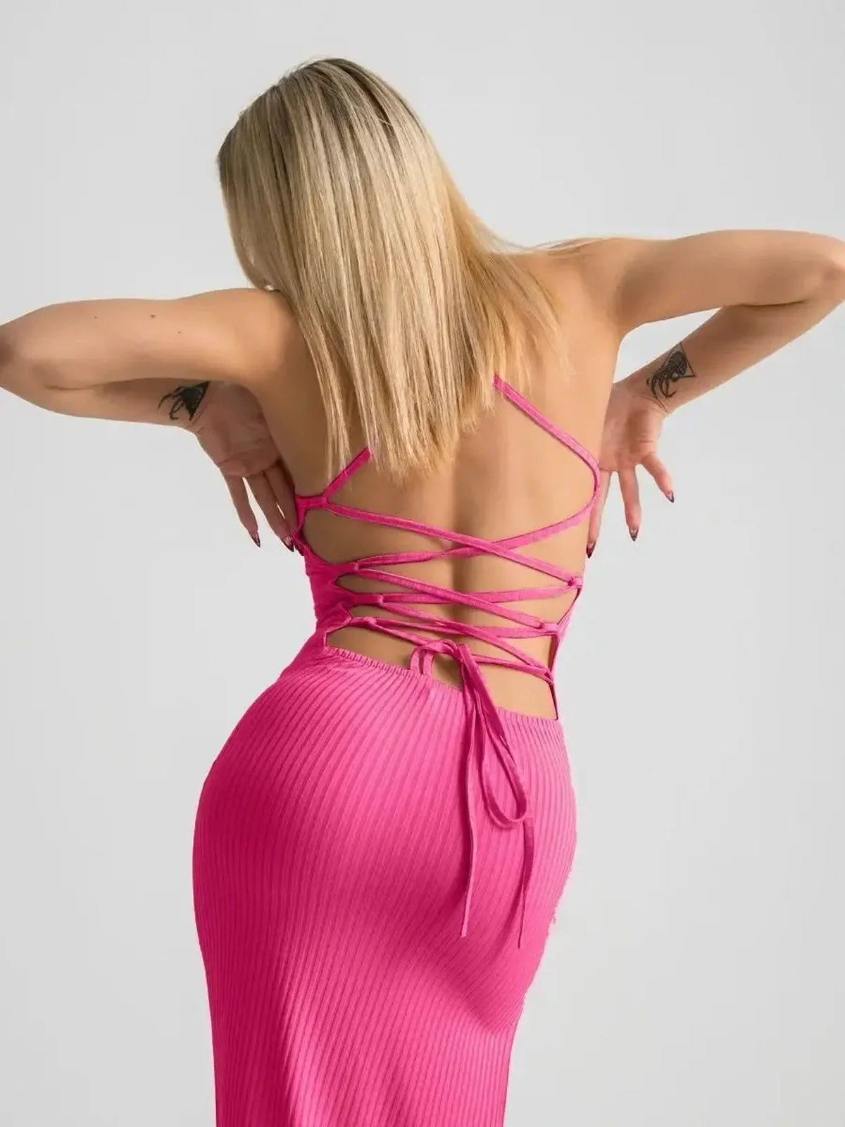 Back view of a woman in a pink Lush Lace Midi Dress featuring a lace-up detail, showcasing a curve-enhancing silhouette.