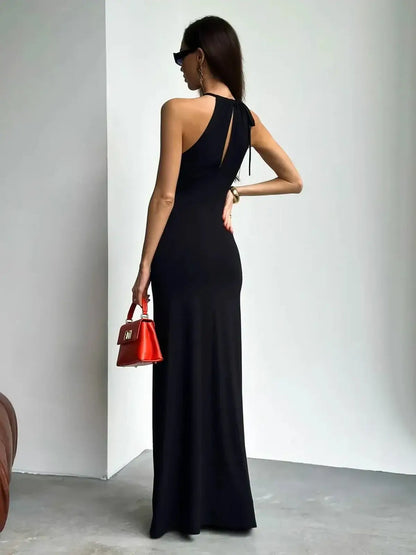 Elegant black maxi dress with halter neckline, ruched design, and chic red handbag, perfect for summer soirées.