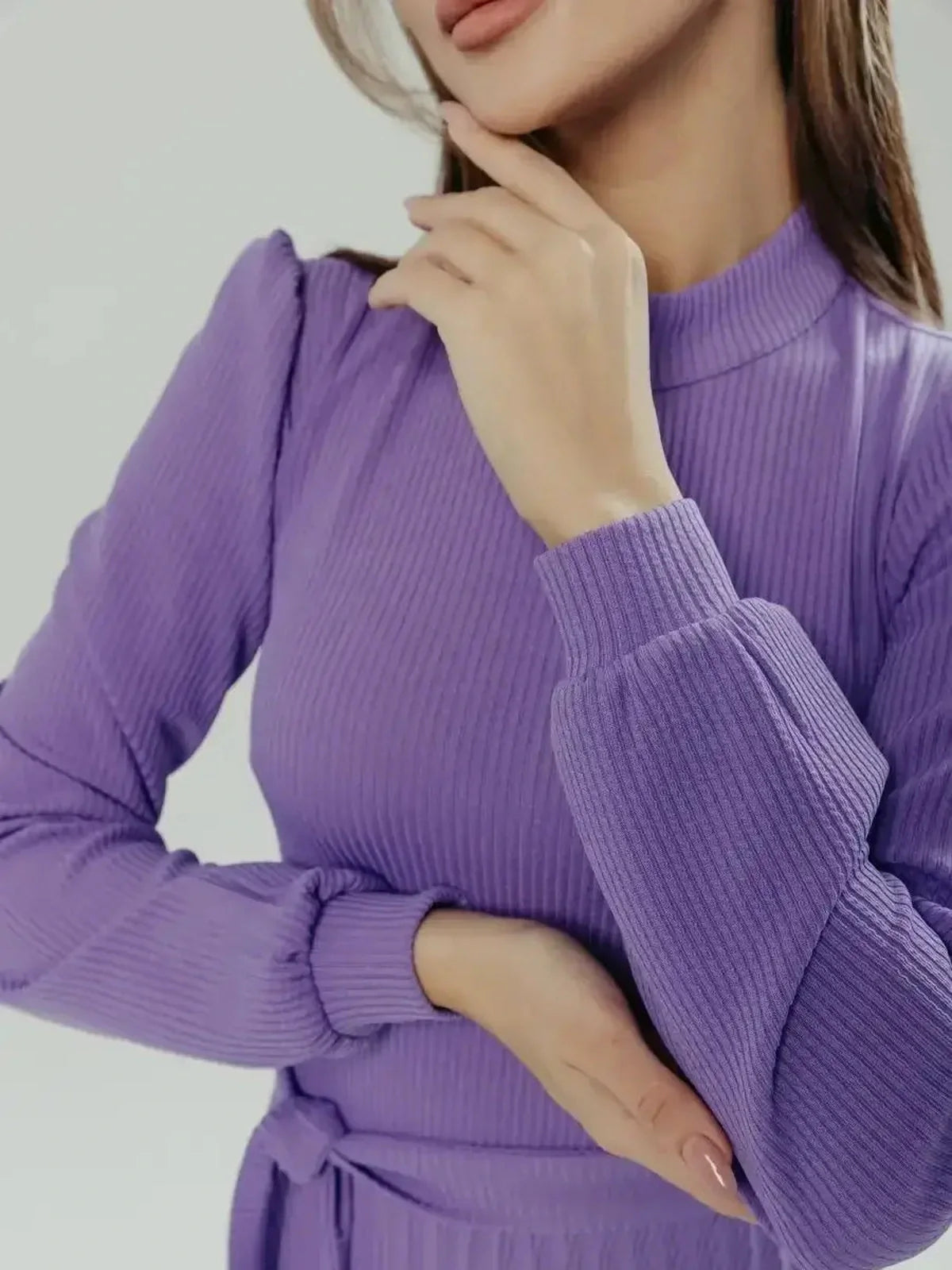 Close-up of a woman in a violet dress featuring ribbed texture and puff sleeves, highlighting elegant design details.