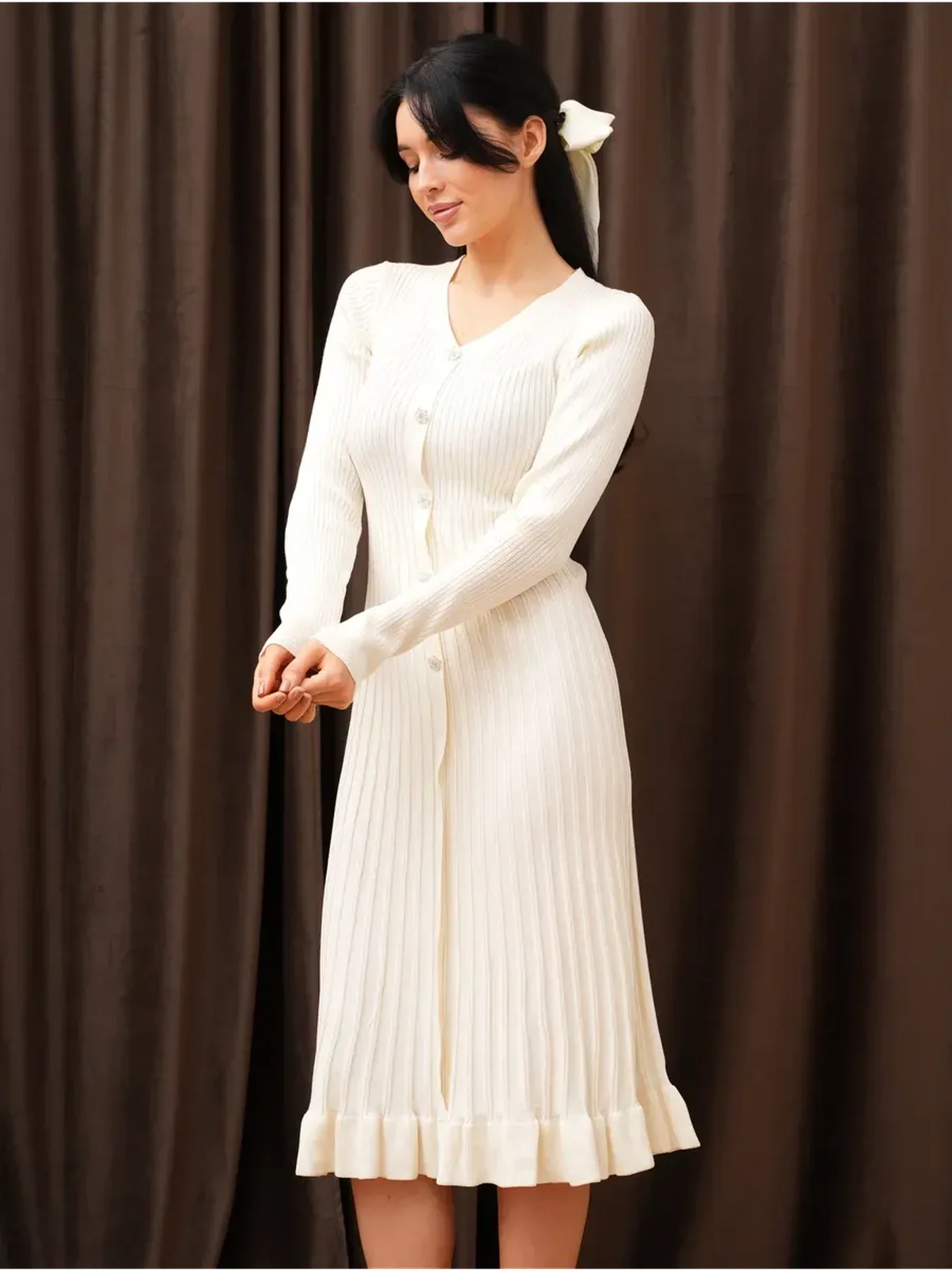 Woman wearing a Pearl Knit Midi Dress with ribbed texture, V-neckline, and long sleeves, perfect for weddings and formal events.