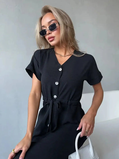 Model wearing the Iconic Ease Midi Dress, a chic black dress with button-front, tie-waist, and breezy sleeves.