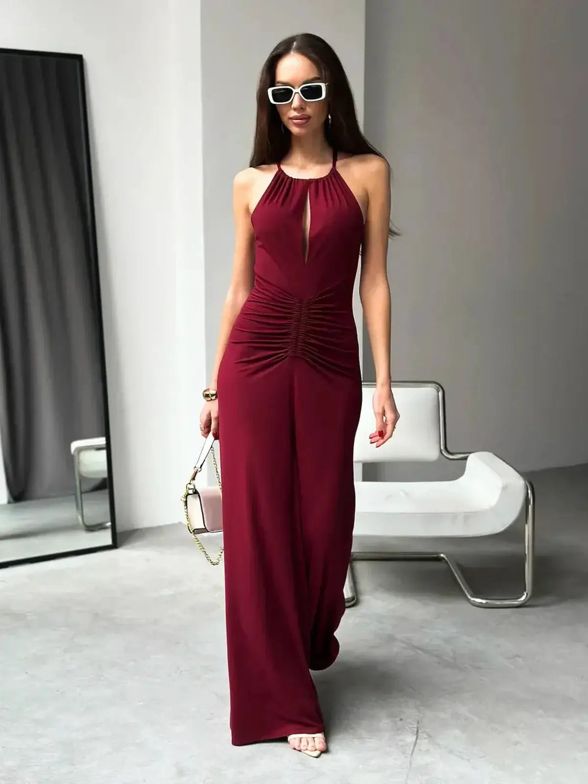 Chic woman in a burgundy maxi dress with halter neckline and ruched waist, ideal for summer events and formal occasions.