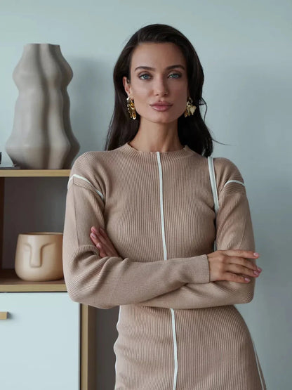 Model wearing a beige sculpted line midi dress with elegant silhouette and minimalist design in a chic indoor setting.