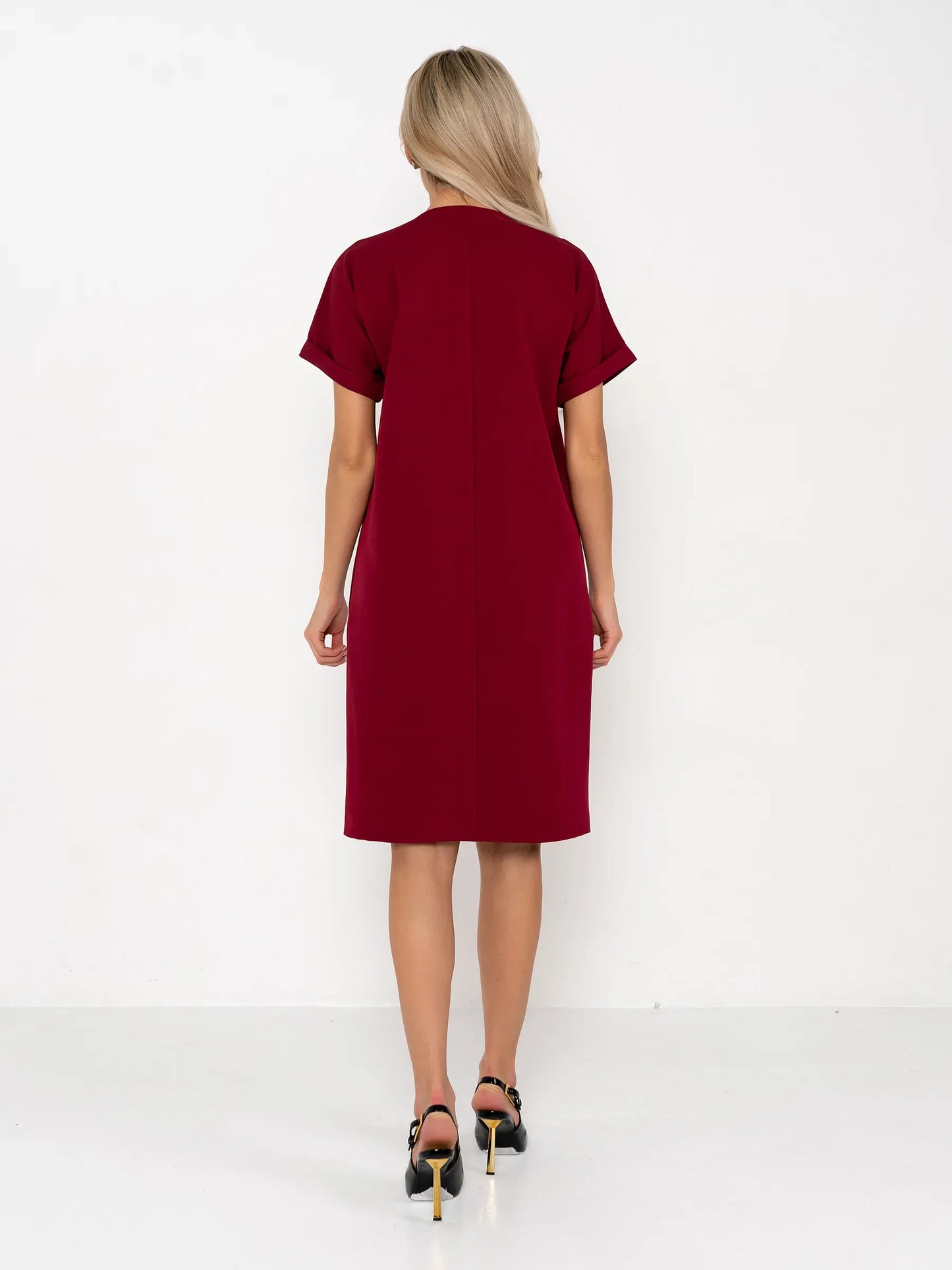 Back view of a woman wearing a crimson mini dress, highlighting its elegant sheath silhouette and short sleeves.