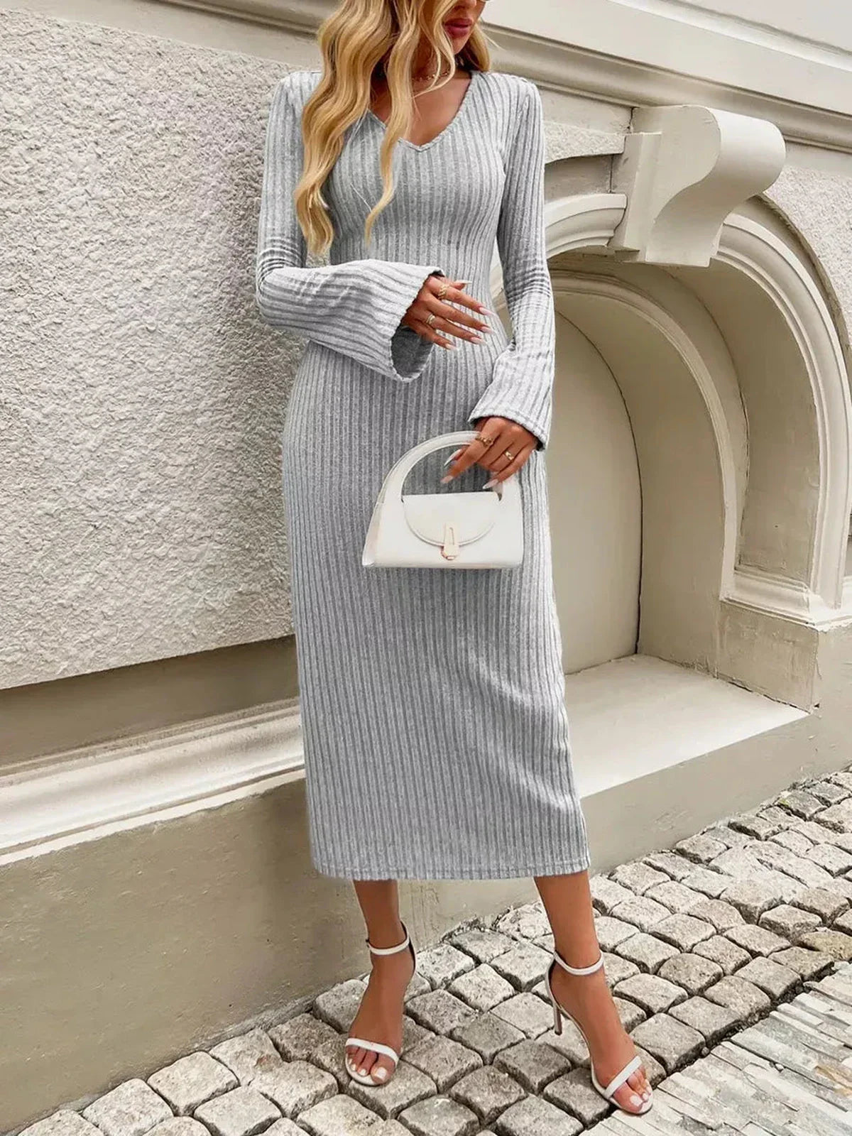 Stylish woman in a sculpted soft midi dress with flared sleeves, holding a handbag, perfect for wedding or formal occasions.